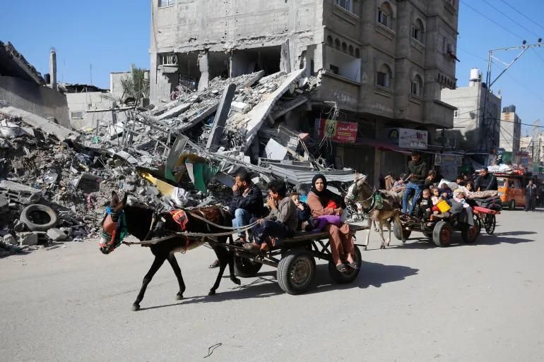 Dans Gaza dévastée, sur une route qui borde des debris et immeuble délabré, deux ânes transportent des personnes en toute sécurité. 
Le premier âne est conduit par un ado. Il a une petite charette et transporte une famille. Les parents et 3 enfants au total. Dont un dans les bras de sa maman. 
Le second à une charrette plus grande. Avec plein de personnes et tout un tas de trucs qu'on ne voit pas bien.