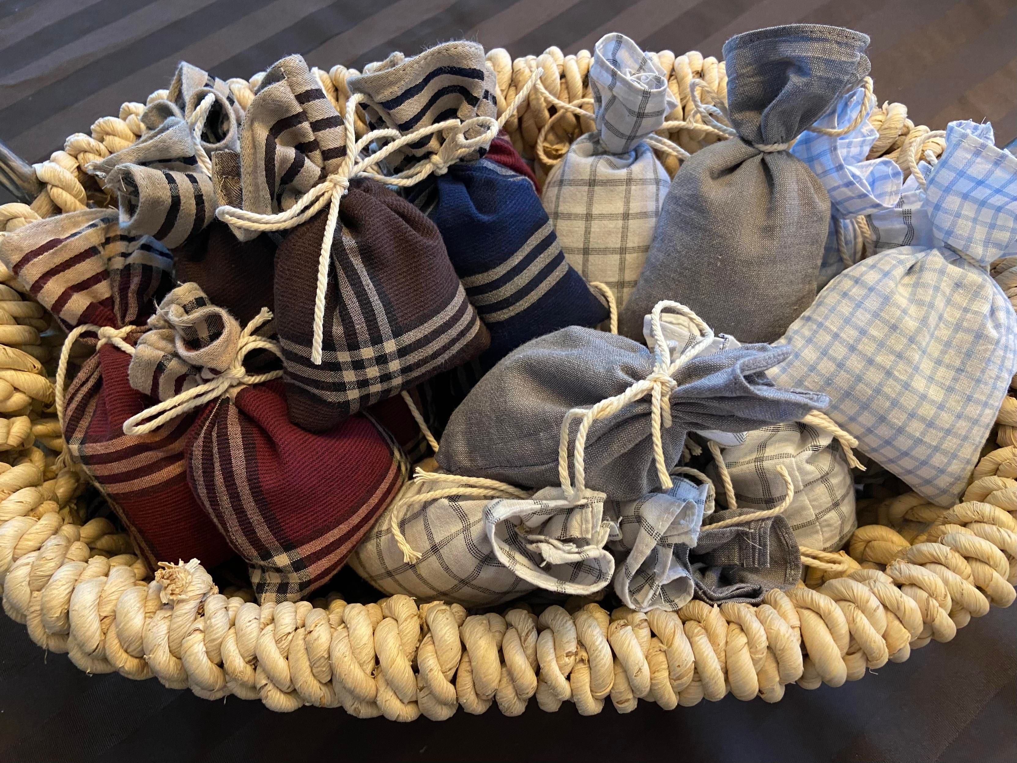 A beige basket full of lavender sachets made from various colors and styles of handkerchiefs. 