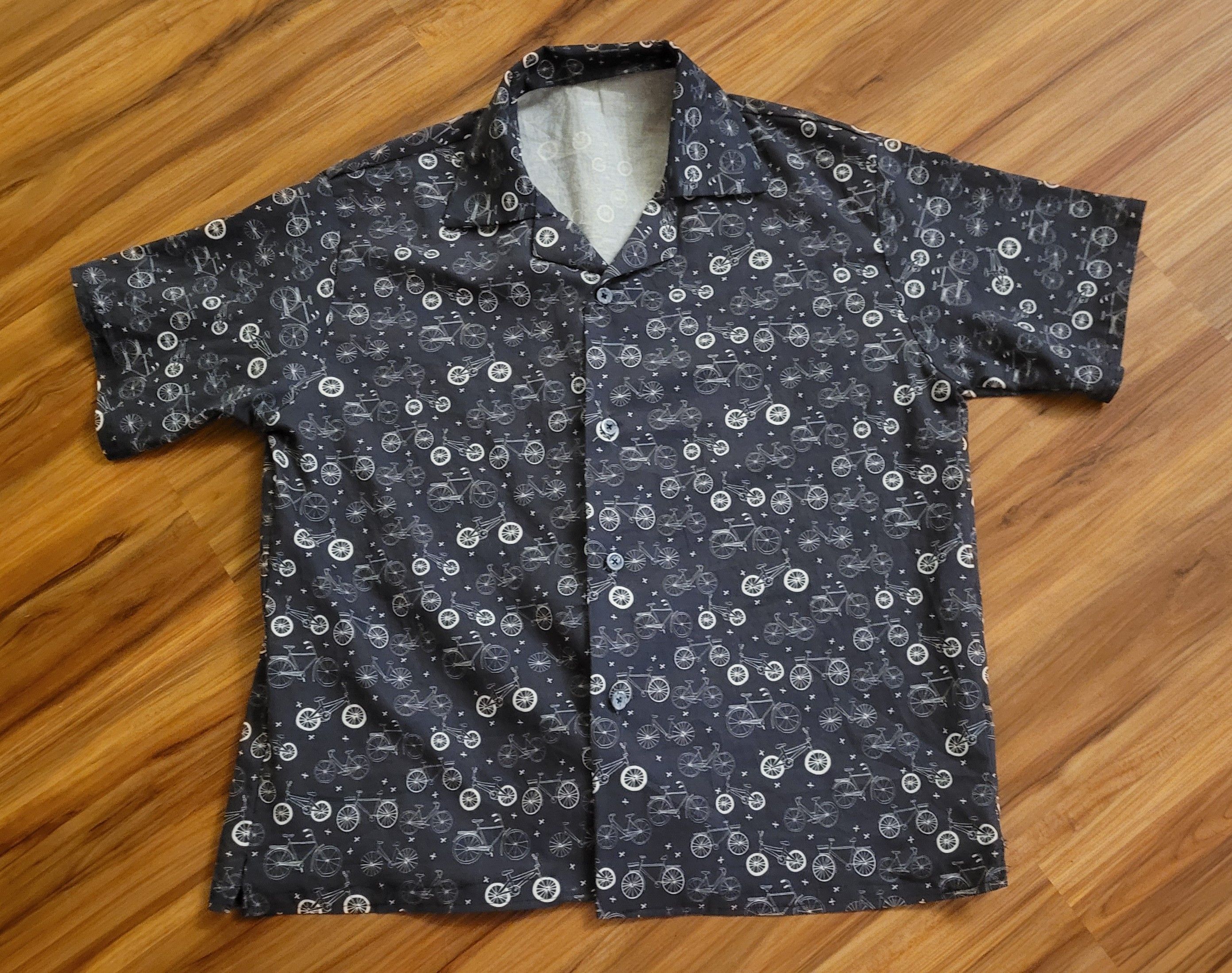 Hawaiian shirt in dark blue, with bicycle pattern, on a wood looking floor