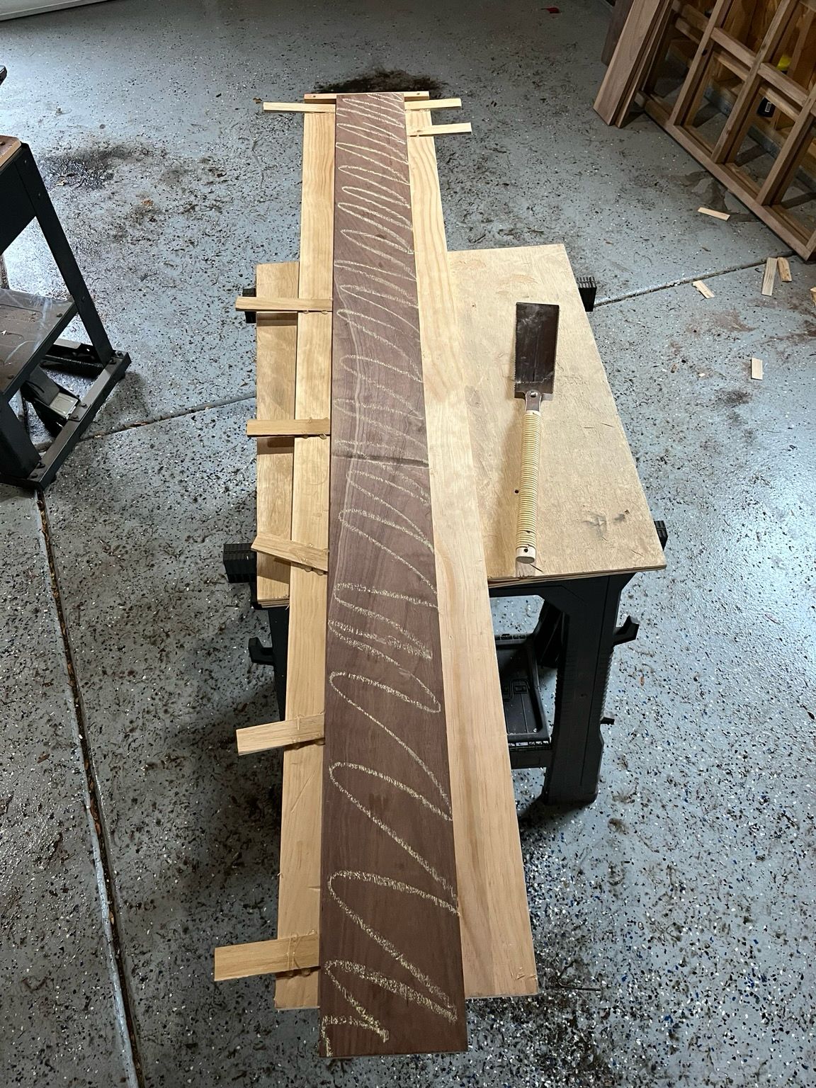 A walnut board on top of a planer sled with eight shims in various locations around the board to keep it flat while it runs through the planer.