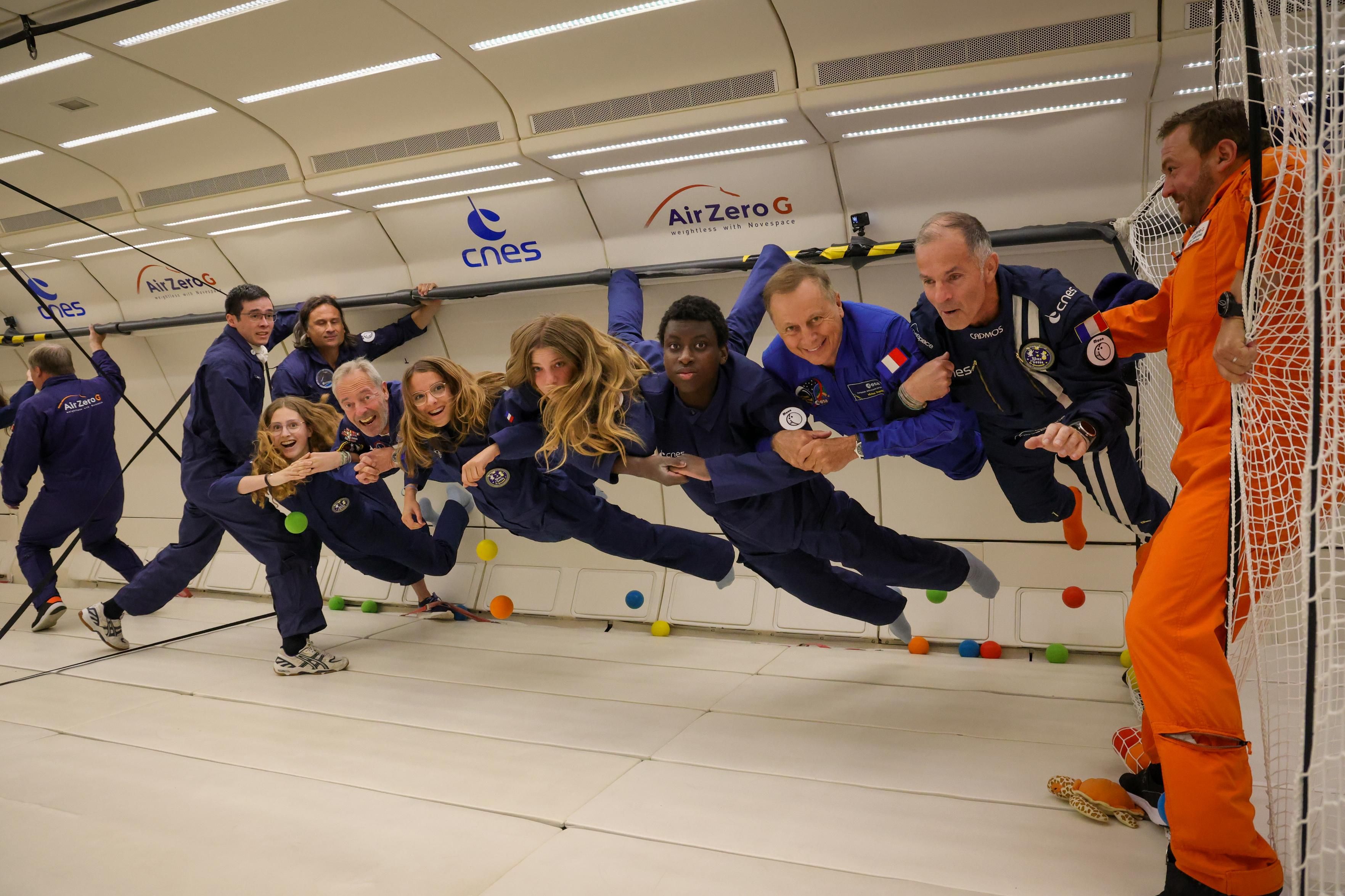 Des élèves lauréats du programme Astronaute d’un jour flottent en apesanteur à l’intérieur de la cabine de l’Airbus A310 ZERO-G de Novespace, entourés d’astronautes français, d’instructeurs de vol parabolique et d’un membre du personnel navigant de sécurité, lors d’un vol réalisé en 2025. © Novespace/Laurent THEILLET, 2025