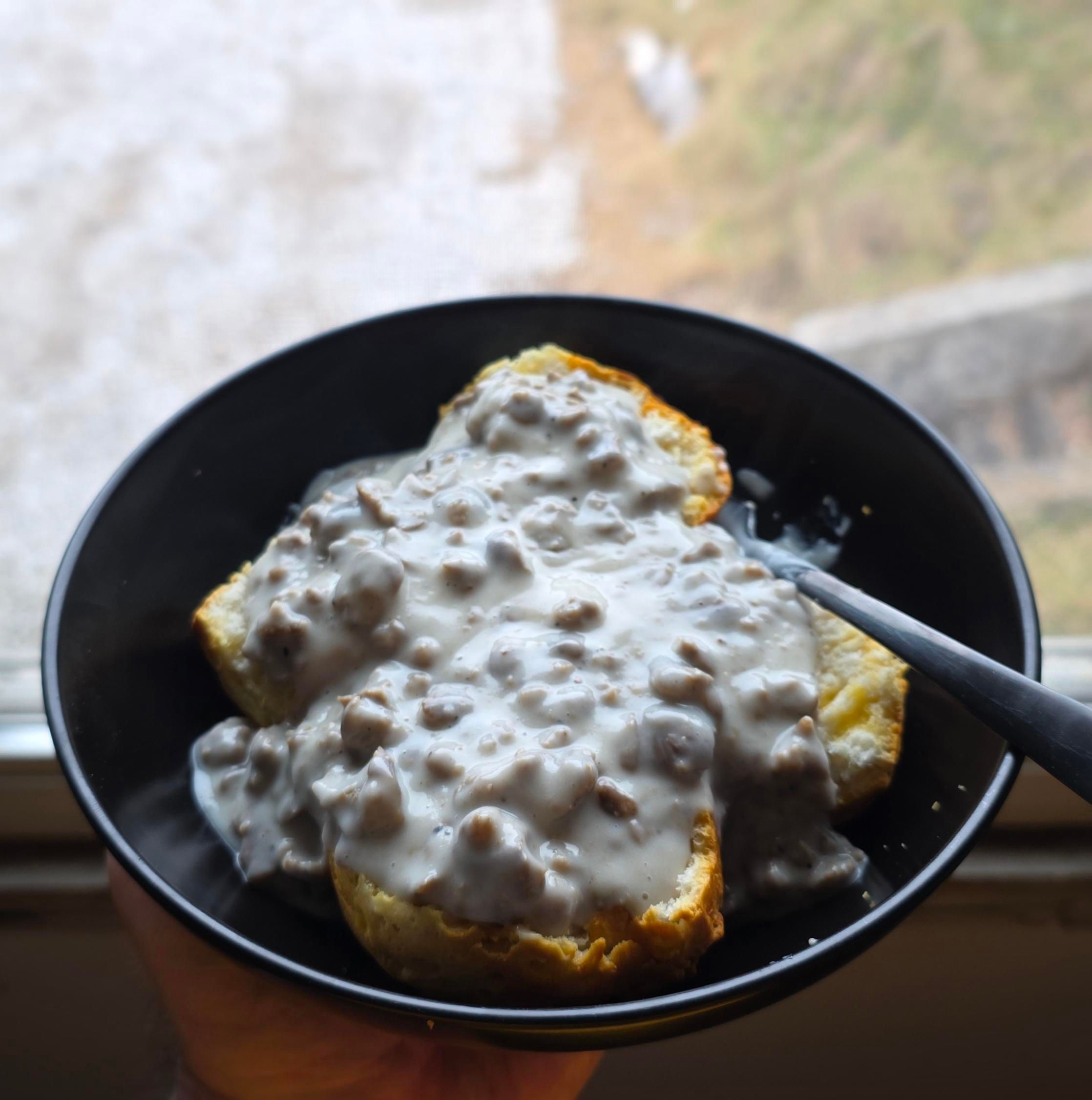 Two split biscuits in a shallow bowl with vegetarian sausage gravy on top.