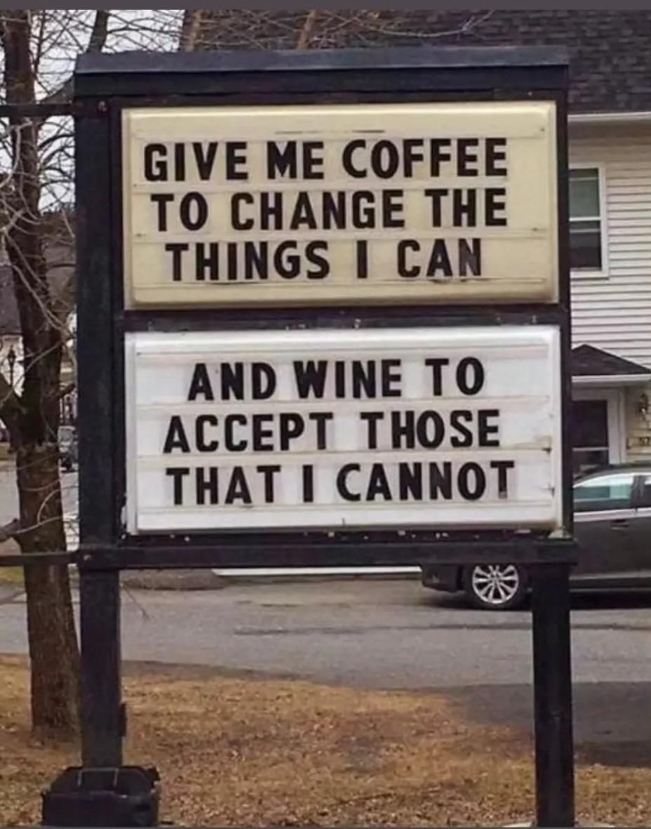 Un cartello nero si trova su un prato verde con alberi sullo sfondo. Il cartello è diviso in due sezioni separate. La sezione superiore contiene il testo: "GIVE ME COFFEE TO CHANGE THE THINGS I CAN". La sezione inferiore contiene il testo: "AND WINE TO ACCEPT THOSE THAT I CANNOT". C'è un edificio e un'auto visibili sullo sfondo.

ALT-TEXT: Un cartello nero presenta due righe di testo su uno sfondo giallo. La prima riga recita "GIVE ME COFFEE TO CHANGE THE THINGS I CAN" e la seconda riga recita "AND WINE TO ACCEPT THOSE THAT I CANNOT".