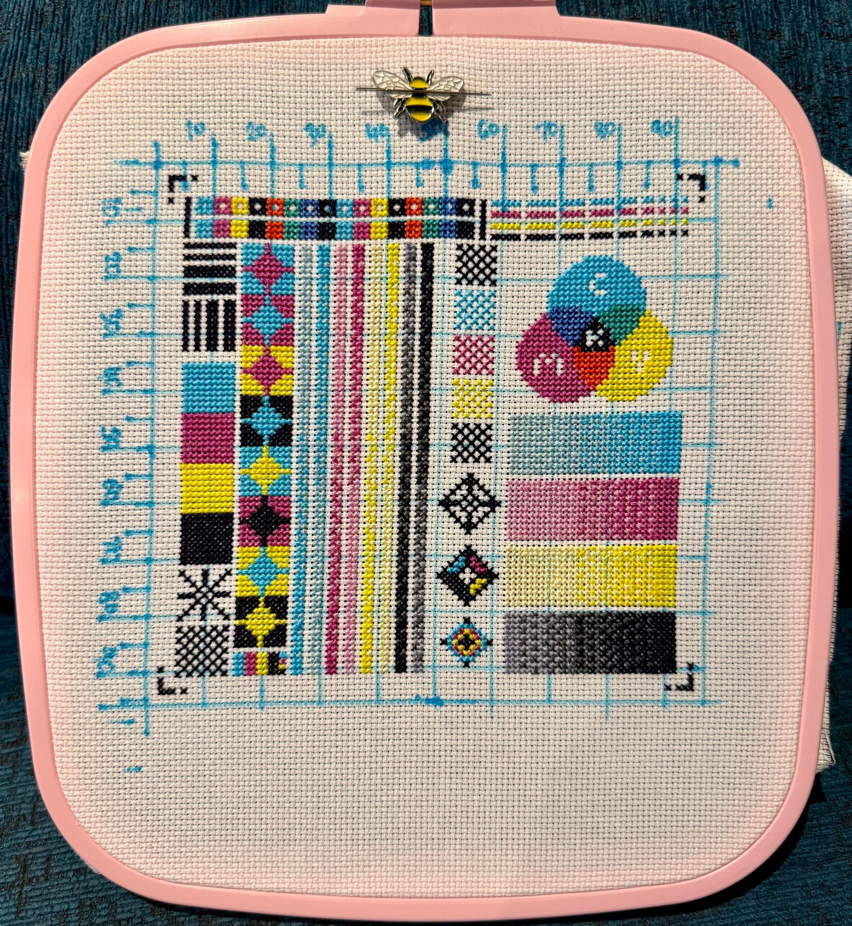 A cross stitch of a printer test page, with blocks of cyan, magenta, yellow, and black in various combinations. In the top right there’s an overlapping area where the colours also combine to make red, blue, and yellow.