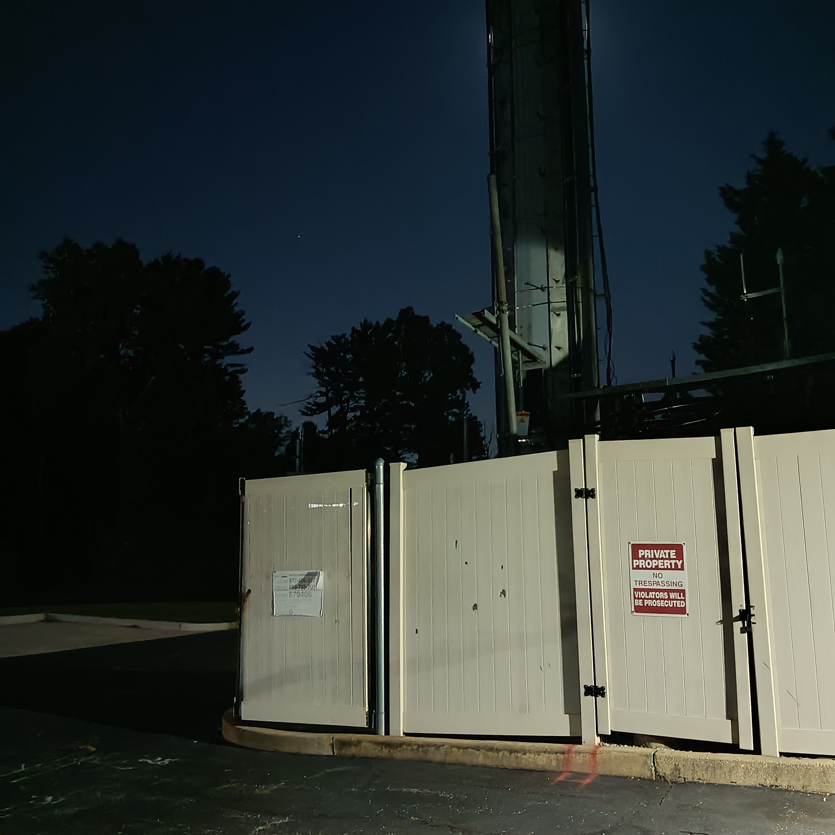 private property signs on the surrounding fence. the radio towers lower half blooms out and covers the full moon.