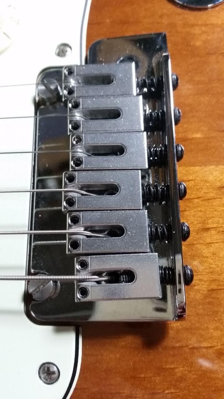 Ponticello di una Fender Stratocaster.
Nei forellini a fianco delle corde ci sono viti a brugola microscopiche.