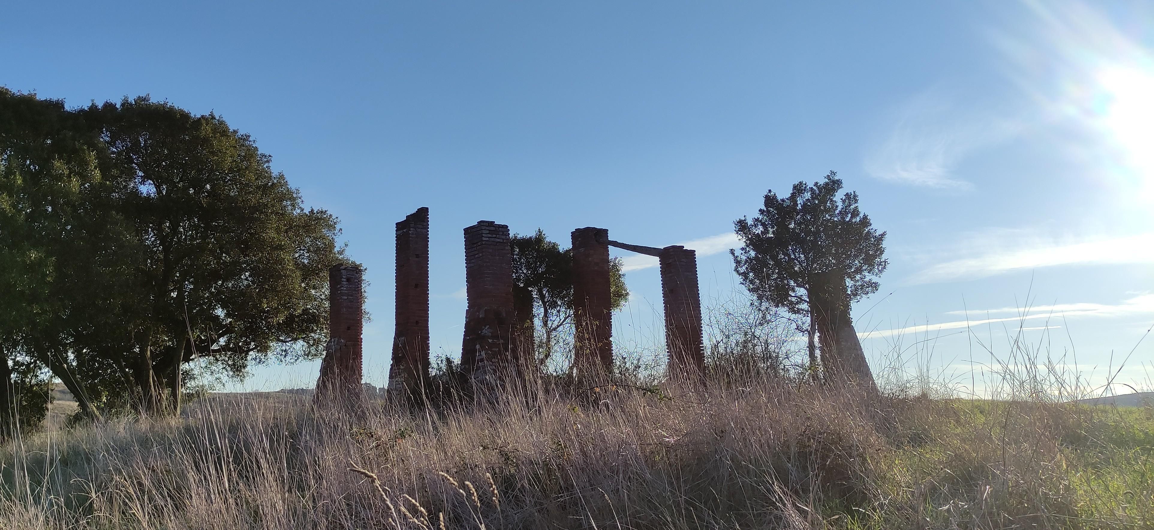 un rudere tra due lecci in cima ad una collina, una specie di Stonehenge in mattoni