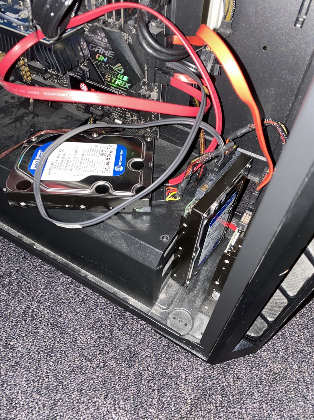 photograph of a computer. there are a few harddrives lying in the case with cables going everywhere. it's very janky