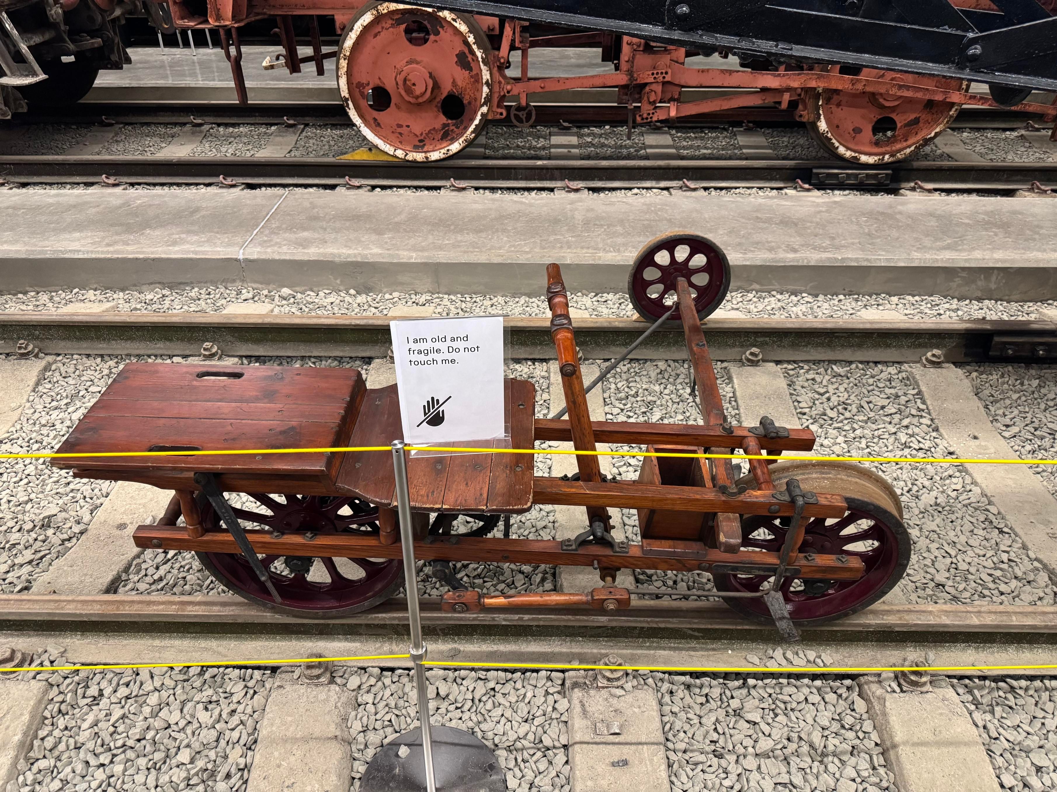 A Buda Platelayer’s velocipede: an 1890s bicycle-like contraption with a third wheel on an outrigger that allows it to rest on the rails safely. There is a mechanism that propels the vehicle by pumping the handlebars.

Atop the vehicle is a sign that says “I am old and fragile. Do not touch me”