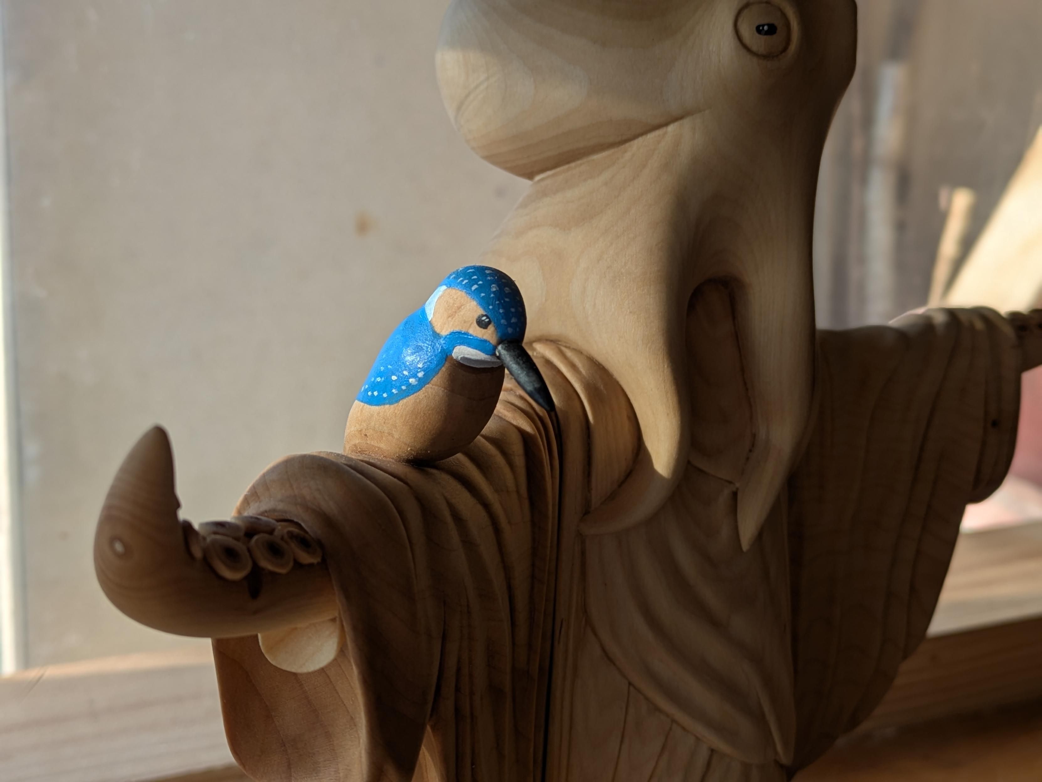 Focus on a kingfisher on the arm of an humanoid octopus wearing a robe 