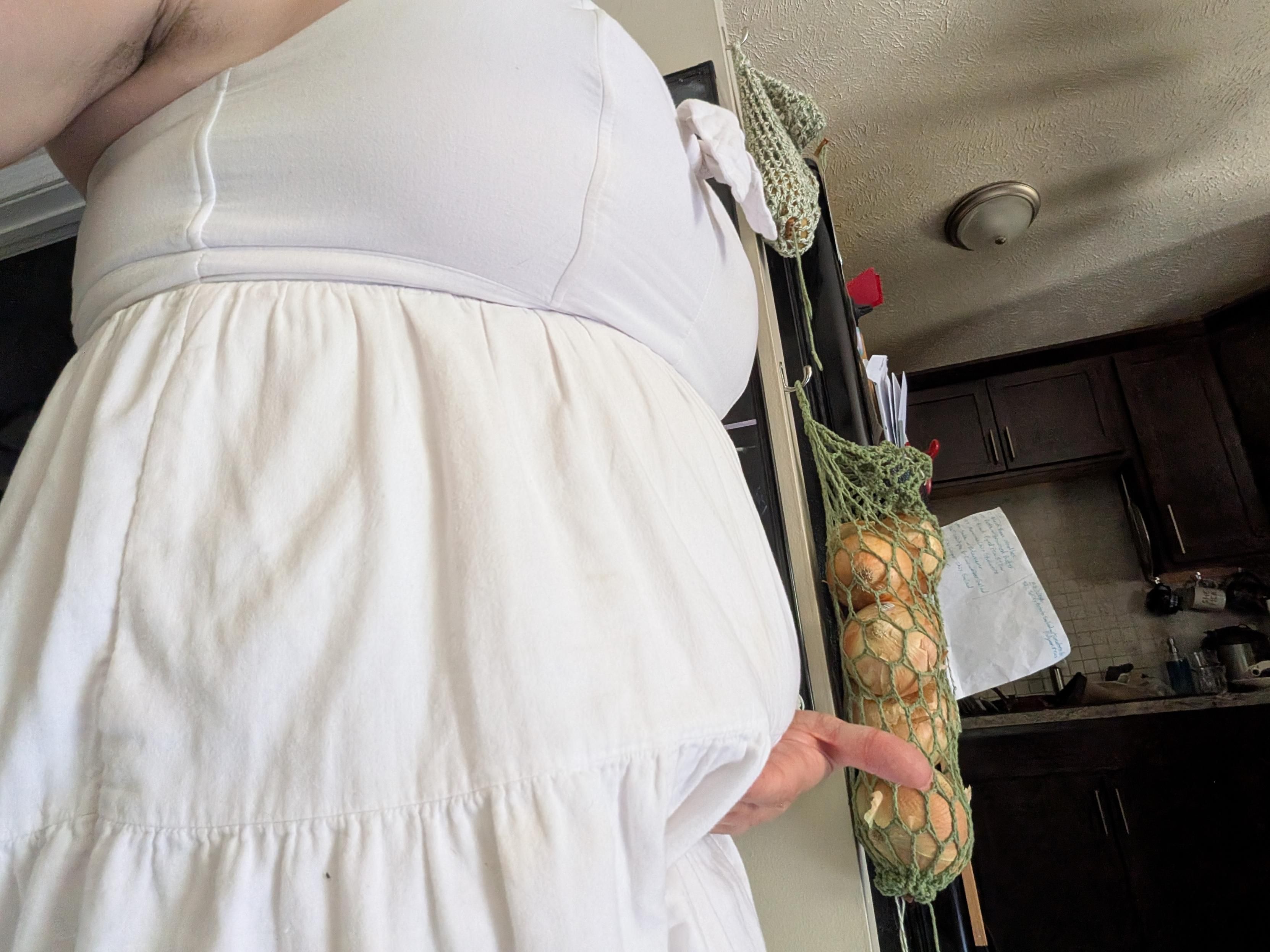 Zoe, holding her dress in to show her apron belly. 