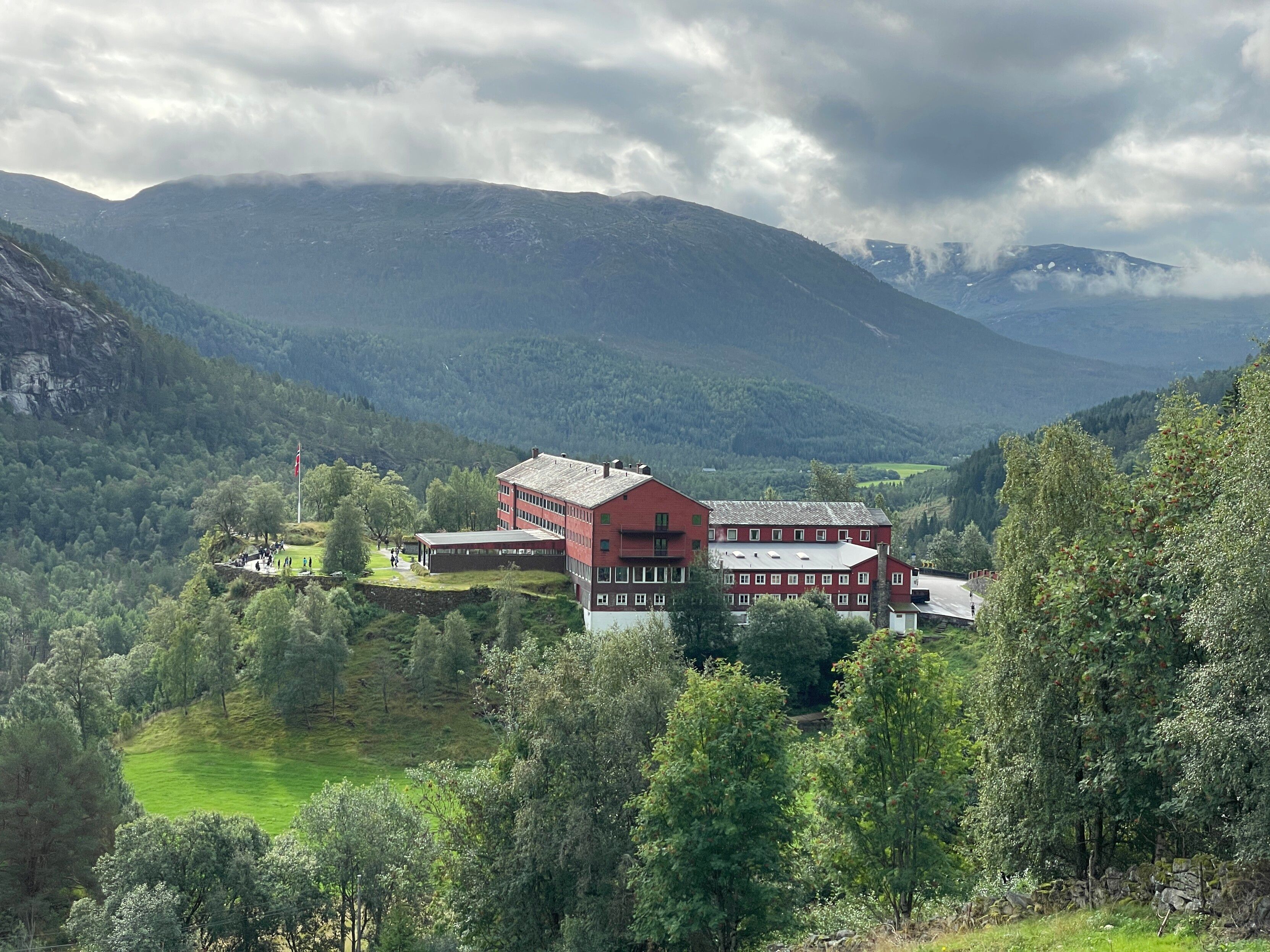 A view of the large red Stalheim hotel on an outlook over the valley, under a foreboding dark overcast sky