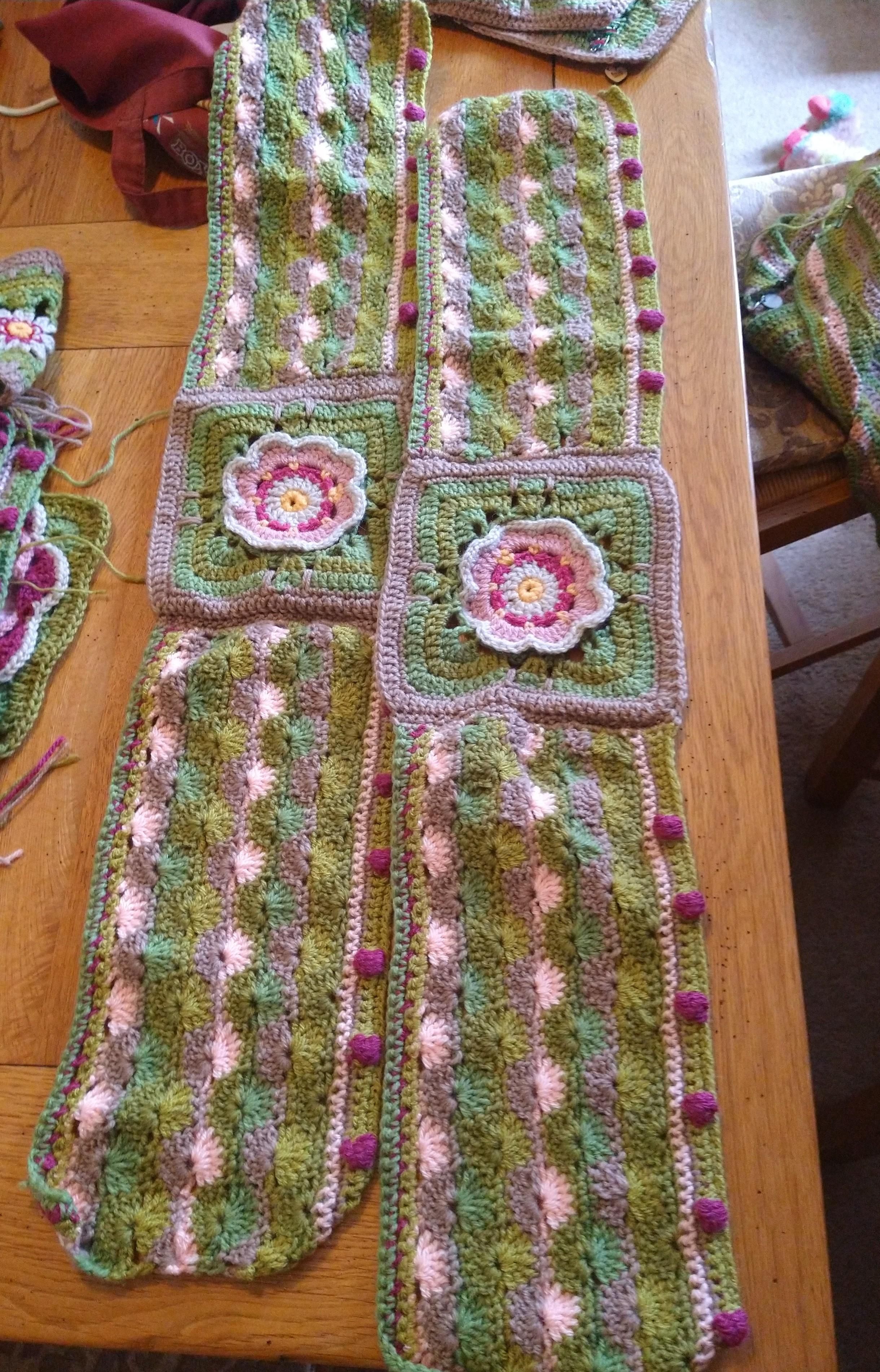 Rectangular crochet blocks in greens and pinks with a flower motif between the two wavy pattern and bobbles 