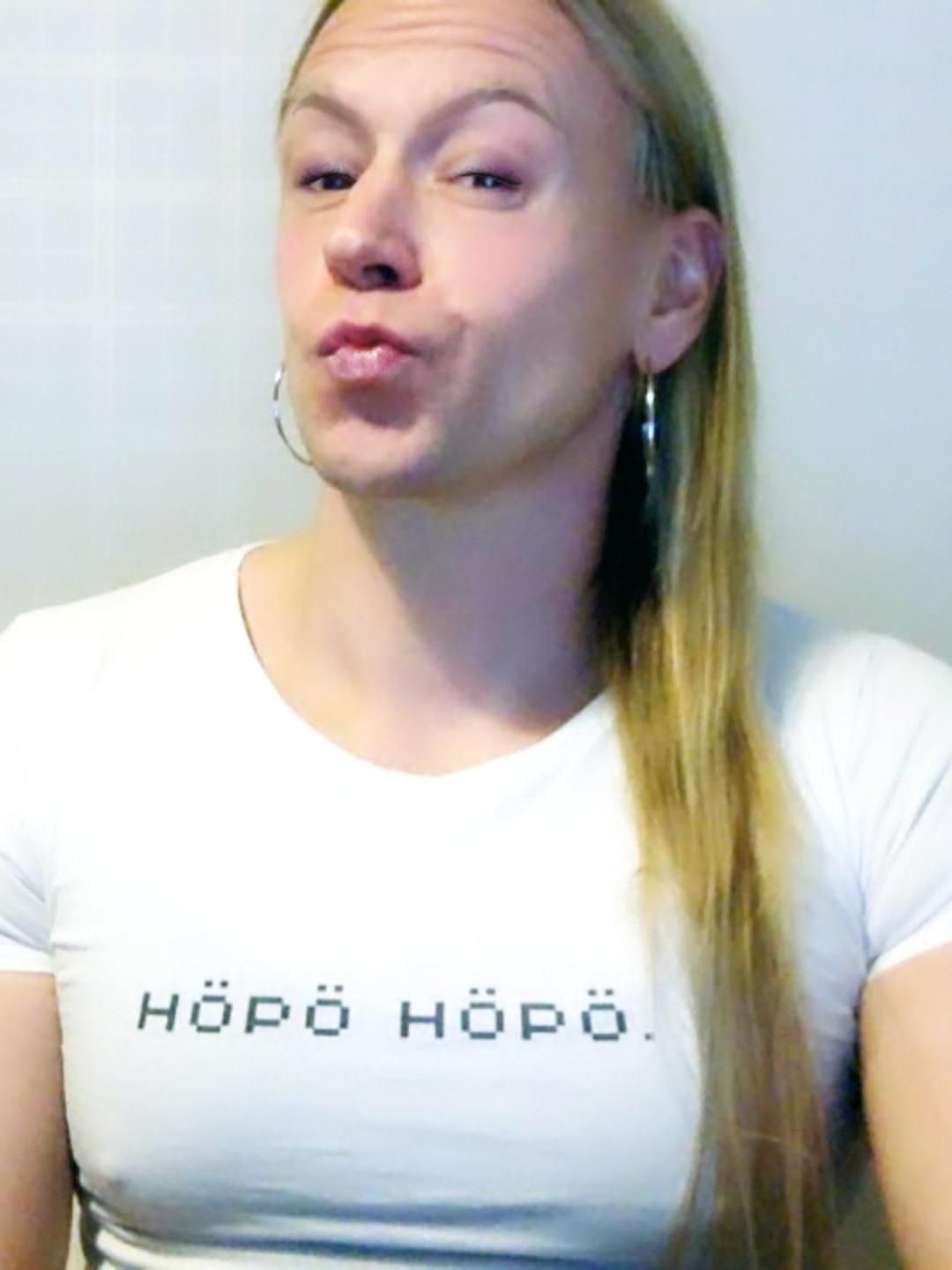 Toottaajan elfie, jossa hänellä on valkoinen paita, jossa lukee mustalla "Höpö höpö".