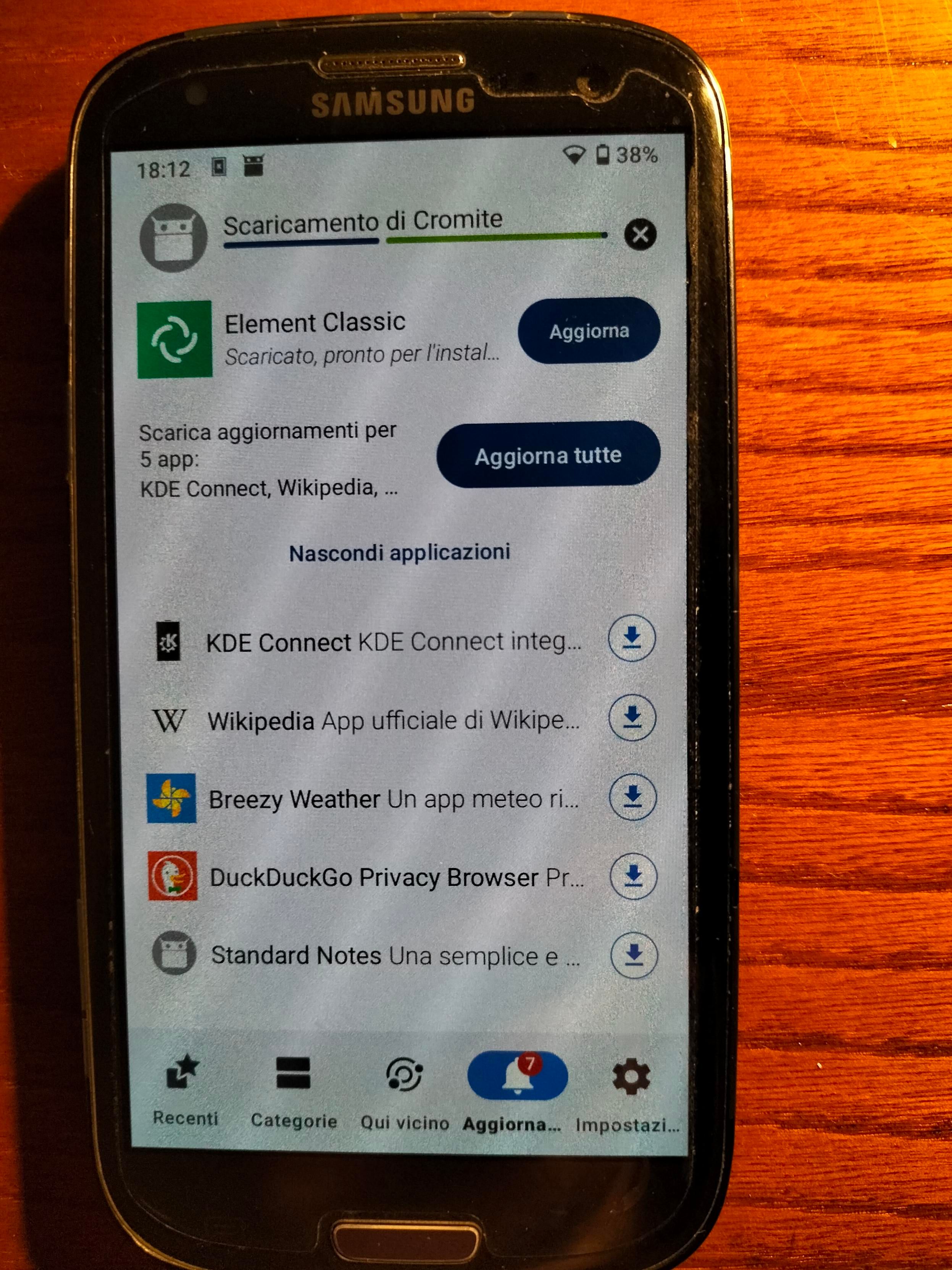Smartphone su una scrivania di colore marrone. Alcune app vengono aggiornate con F-droid.
