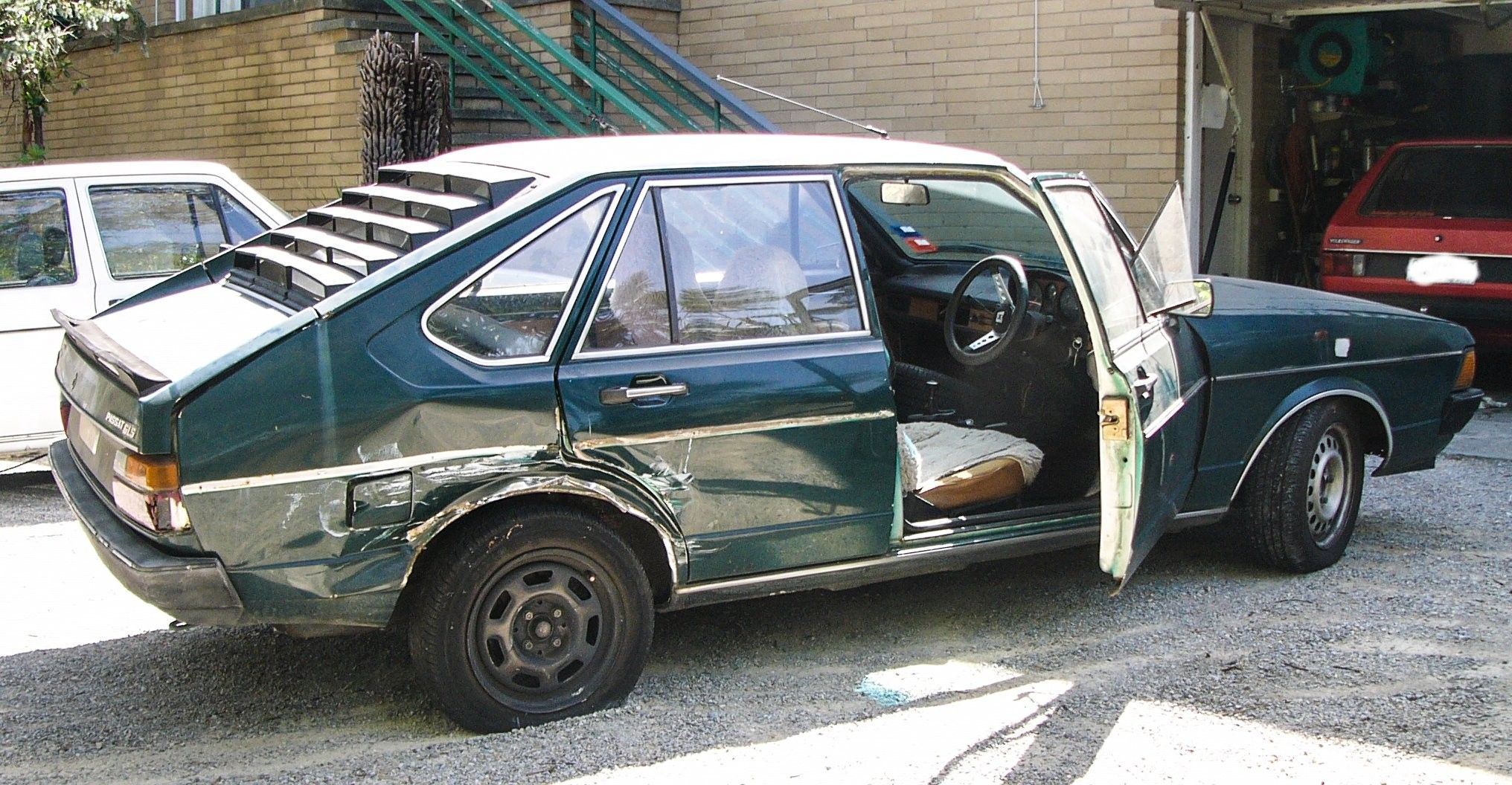 VW Passat in British Racing Green with smashed in rear drivers side wheel arch.