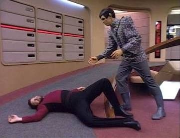 A Romulan looking over Riker who is laid out on the bridge 