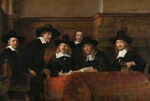 Oil painting.
Group portrait unveiled in 1662 by artist Rembrandt Harmenszoon van Rijn. Depicting the cloth inspectors of the Amsterdam Drapers' Guild. Currently hangs in the Rijksmuseum Amsterdam. Dutch name: De waardijns van het Amsterdamse lakenbereidersgilde.