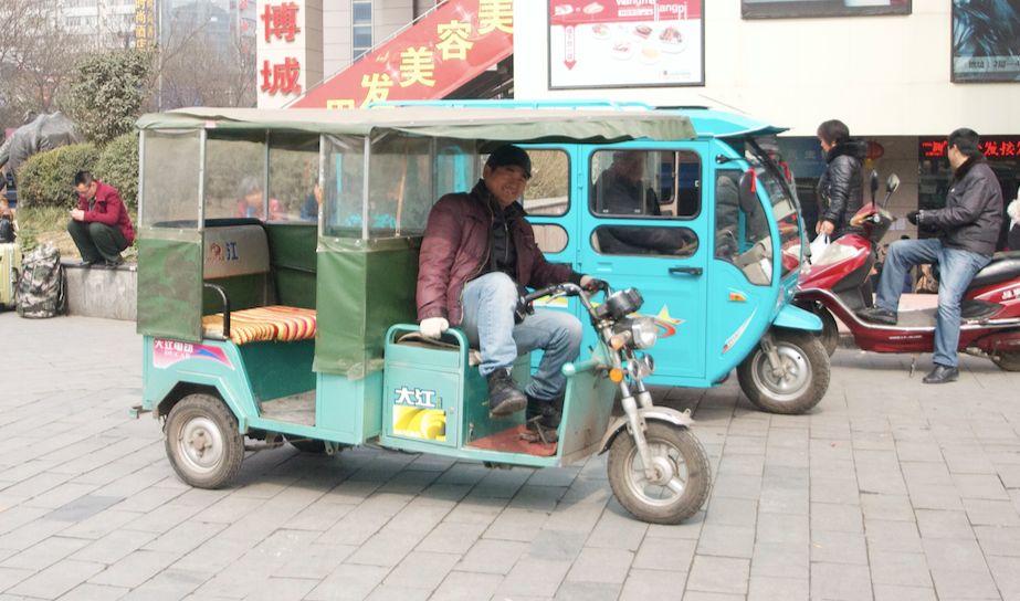 a smiling man moves to get out of his tuktuk