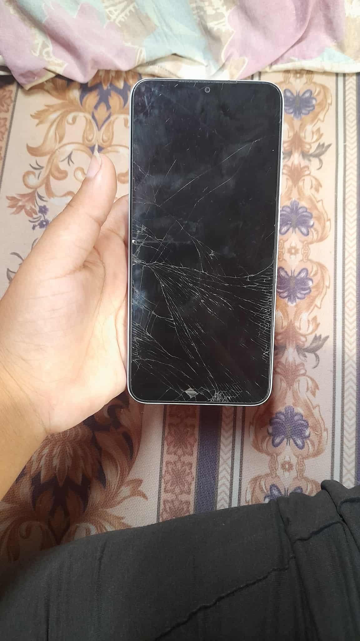 Picture of Naeema holding her phone. We can see that the shield is cracked.