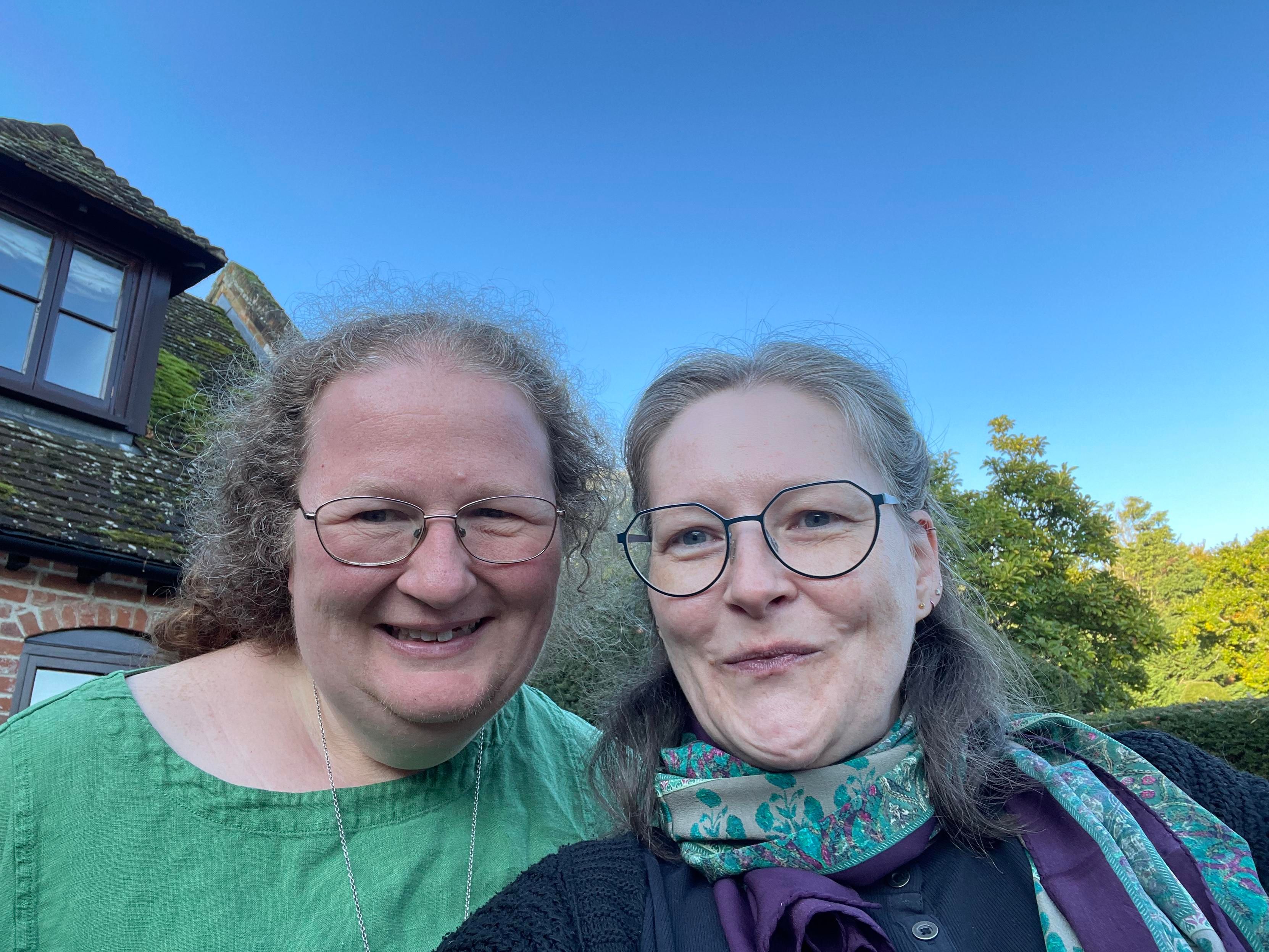 Photo of Cressida (left) and me (right), both looking quite happy in front of an old house in Kent and a clear blue sky.