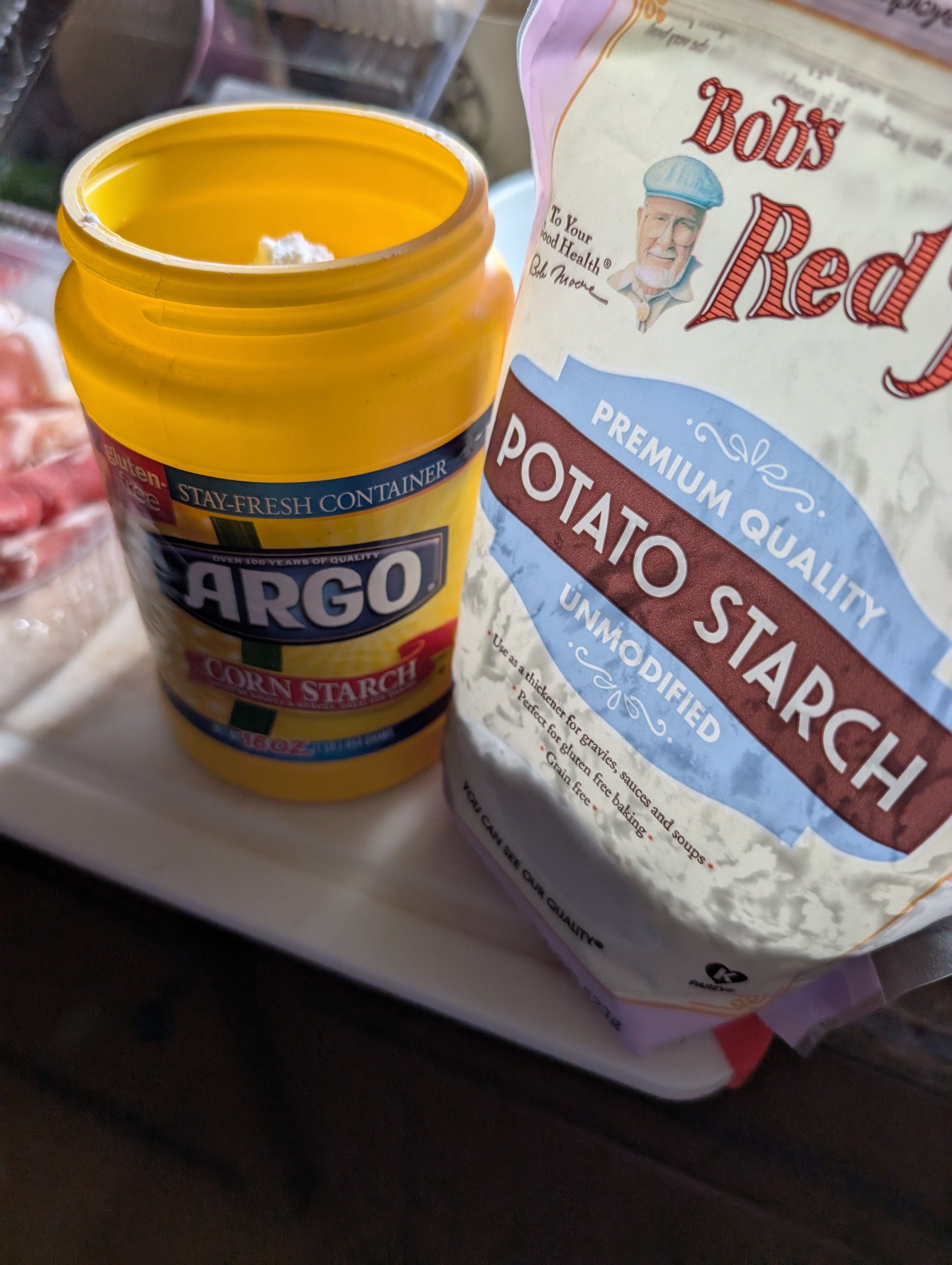 A corn starch canister that is filled with potato starch sitting next to a bag of potato starch