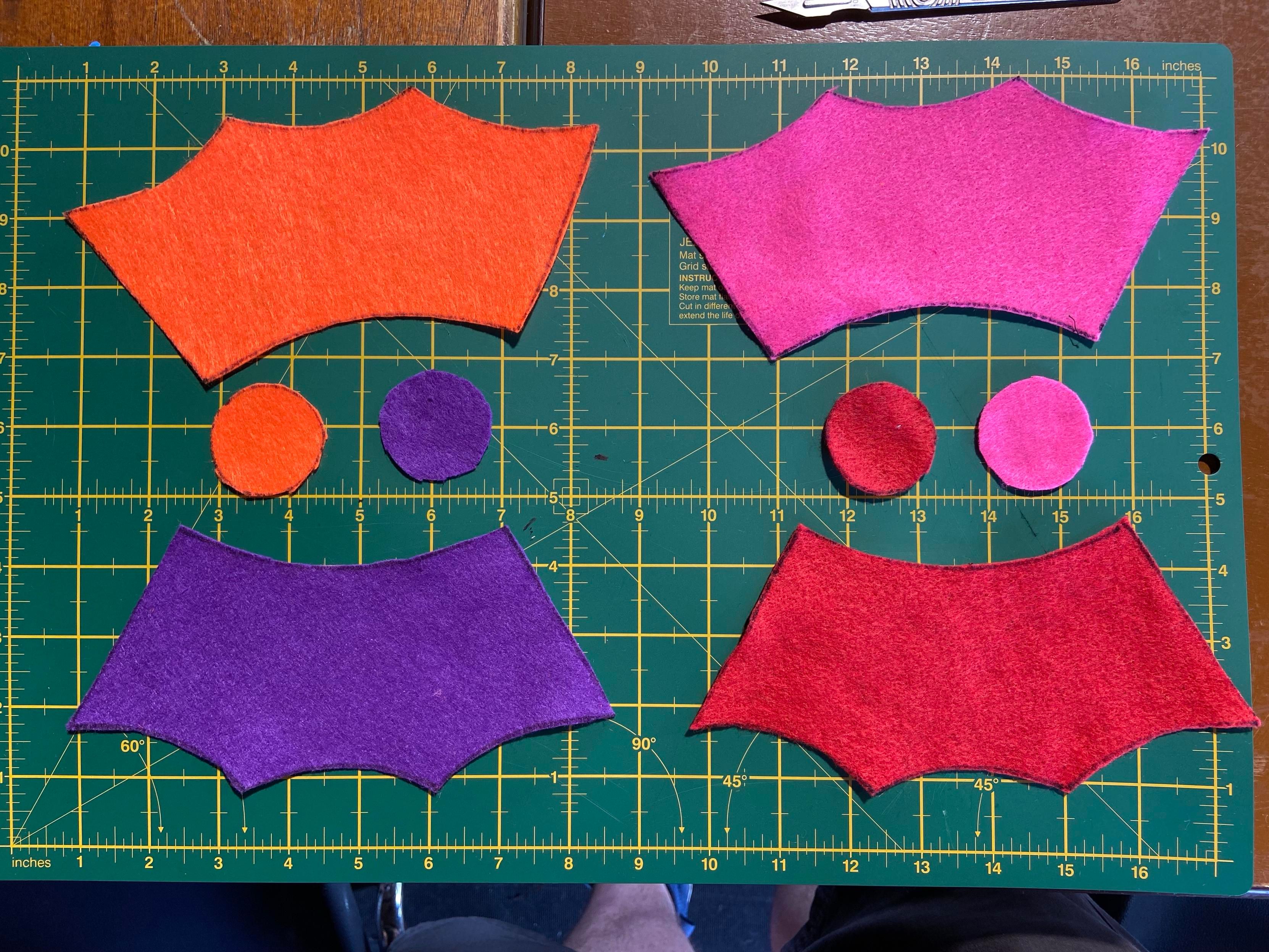 A photo of the cut fabric for the plush: 4 circles, and 4 longer shapes which look kind of like a wing of a bat.