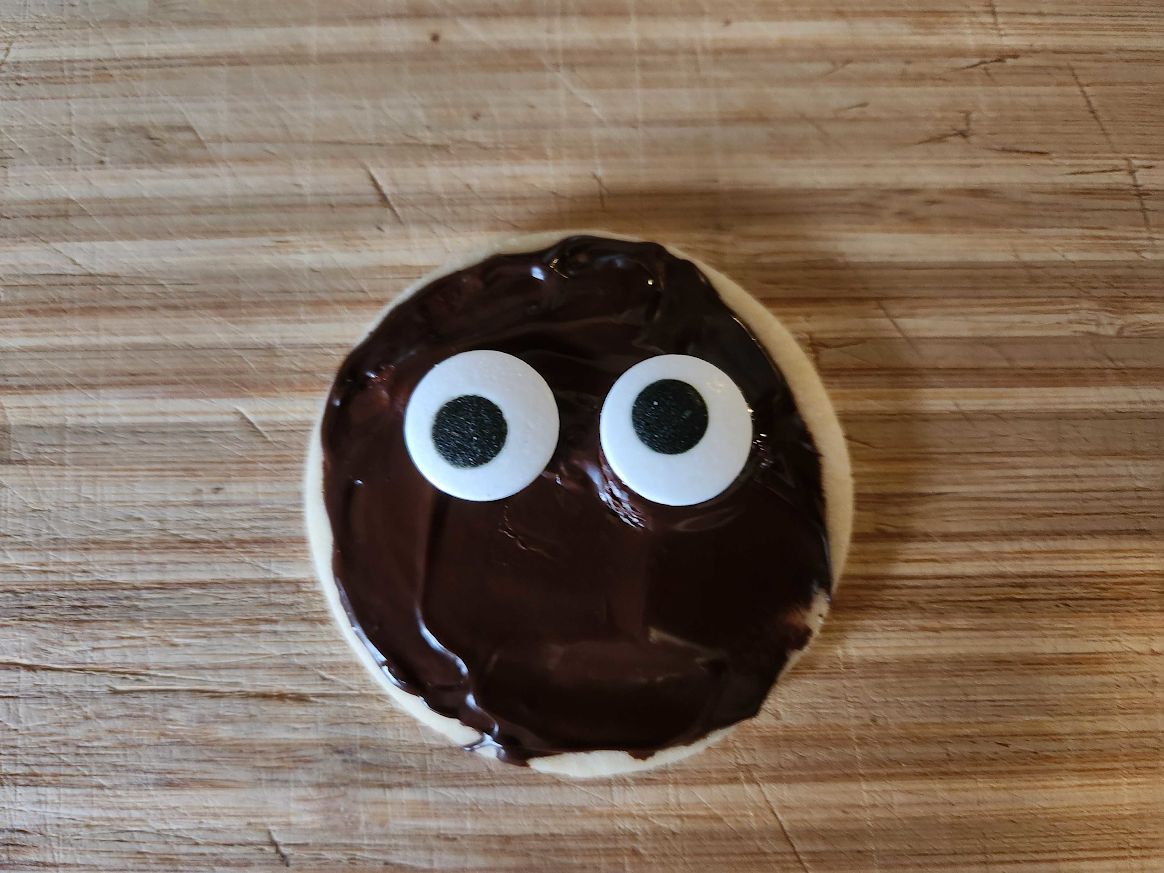 Round shortbread cookie with chocolate and googly eyes.
