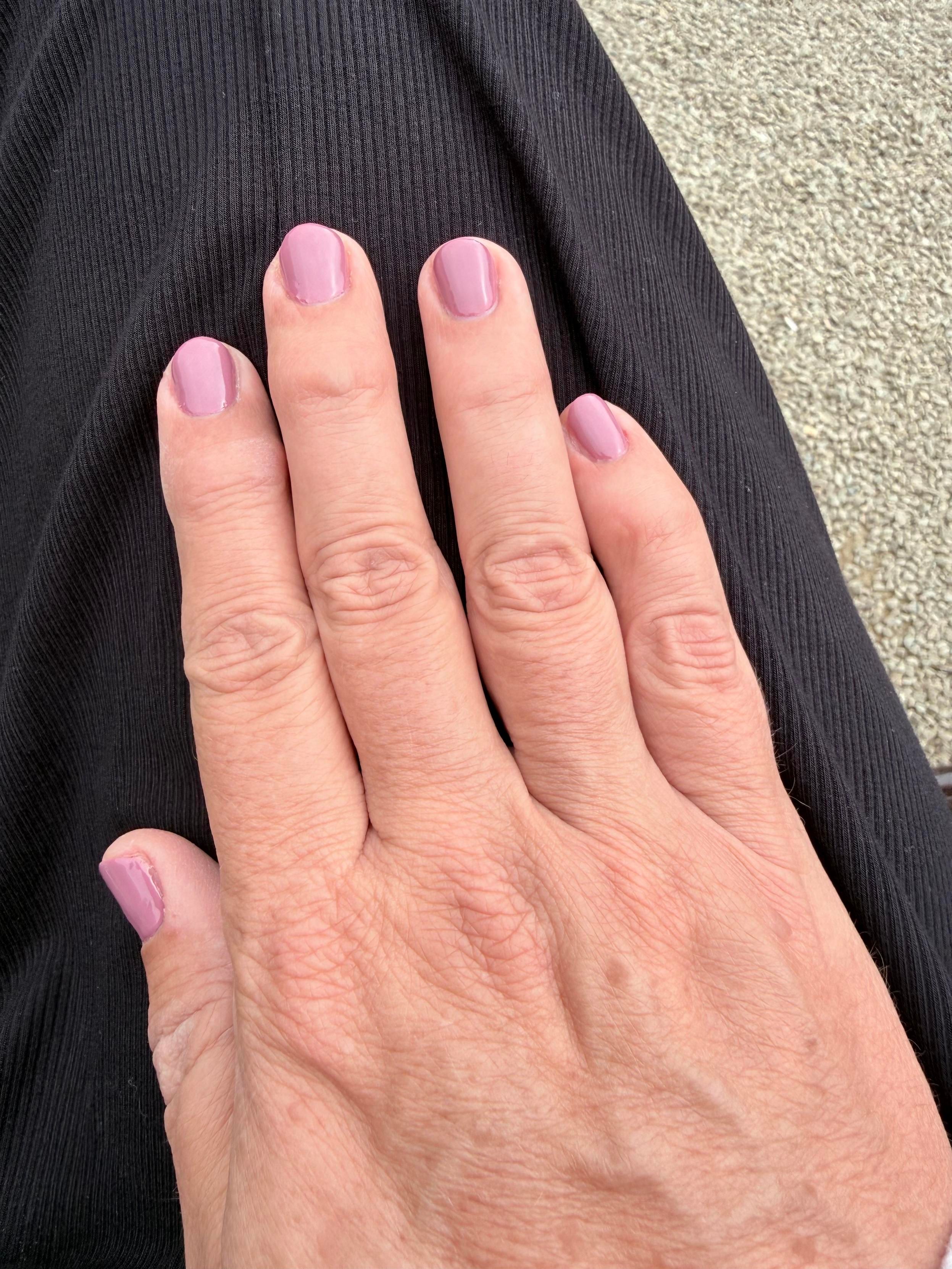 Picture of Sophie’s hand with freshly done purple gel nail polish.