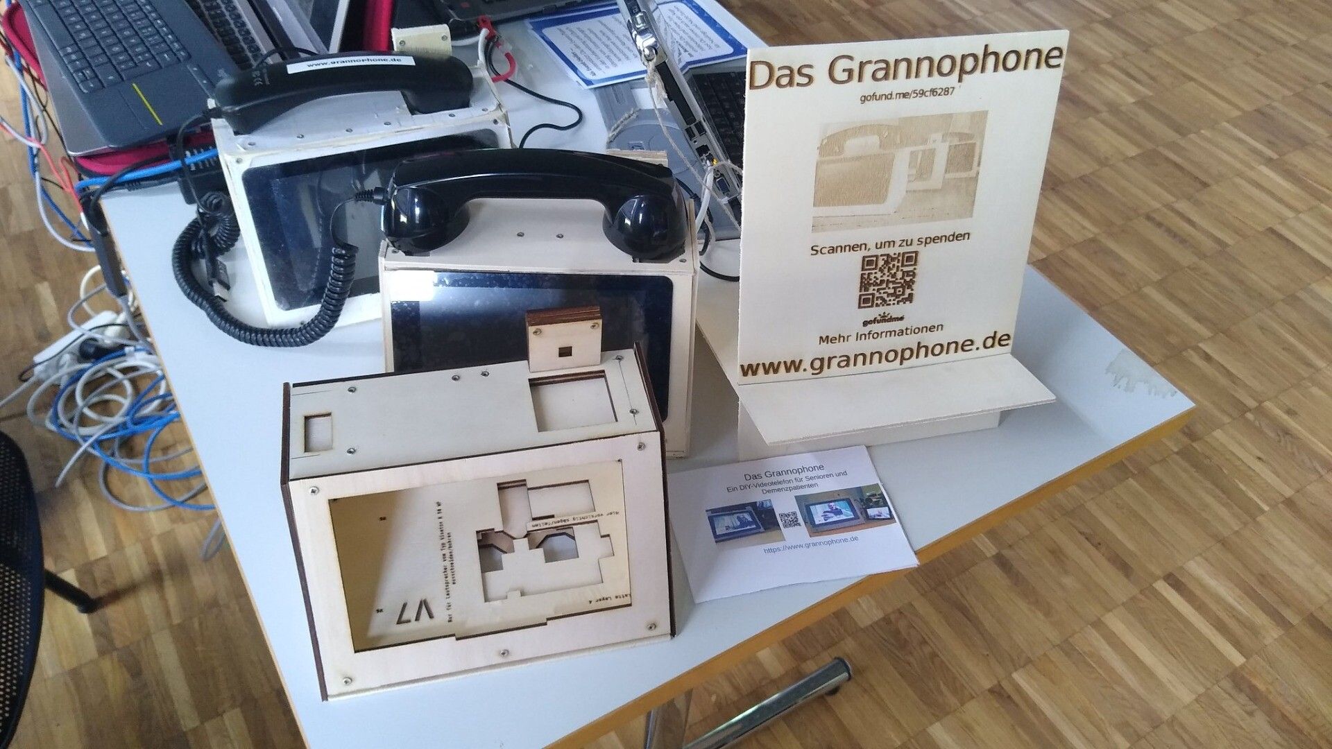 Drei Grannophone-Prototypen und ein Werbeschild auf einem Tisch