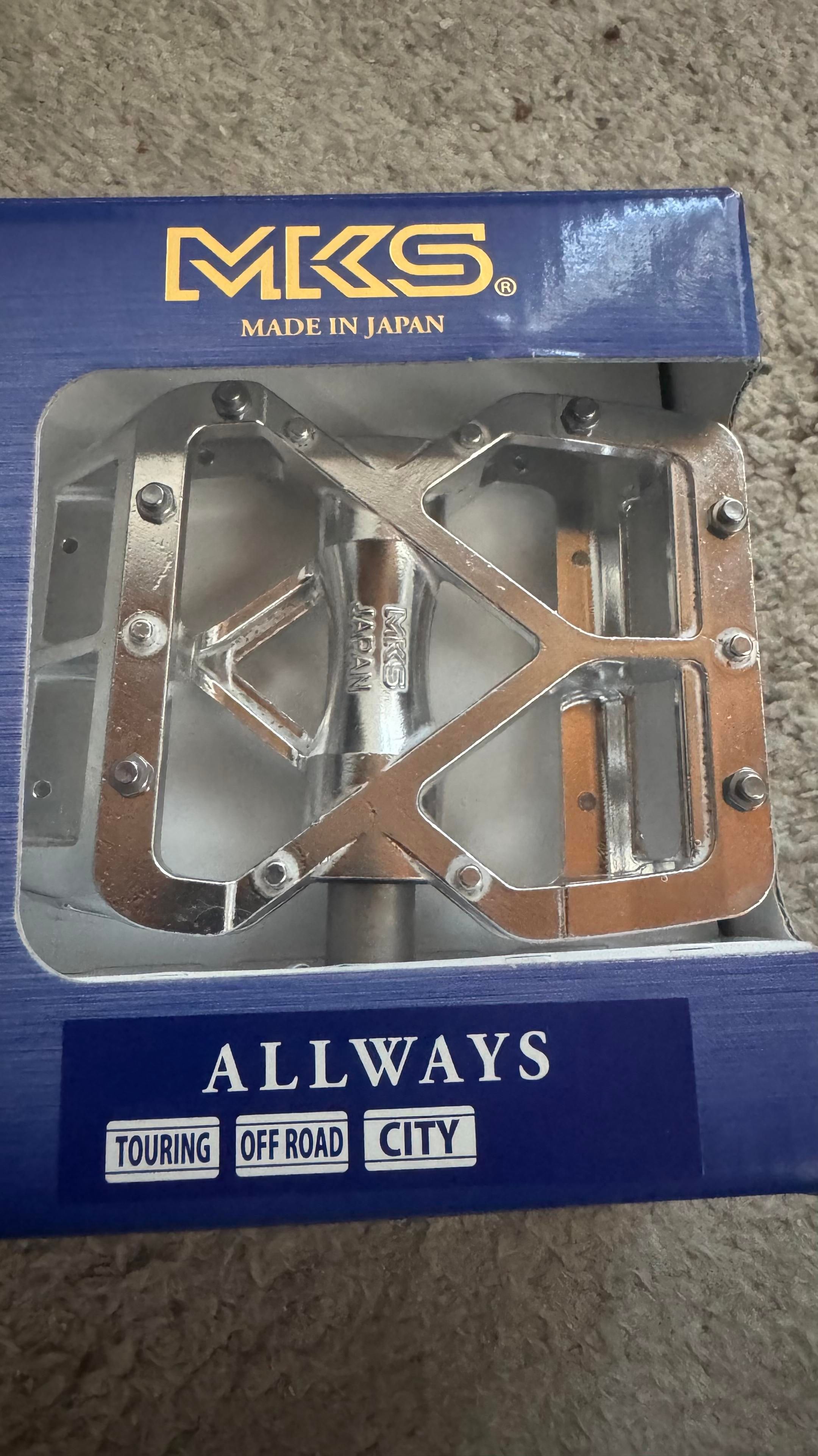 Ein Fahrradpedal-Set, verpackt in einer blauen Schachtel mit der Aufschrift "MKS Made in Japan" und "ALLWAYS". Das Pedal ist für den Touring-, Offroad- und Stadtgebrauch konzipiert.