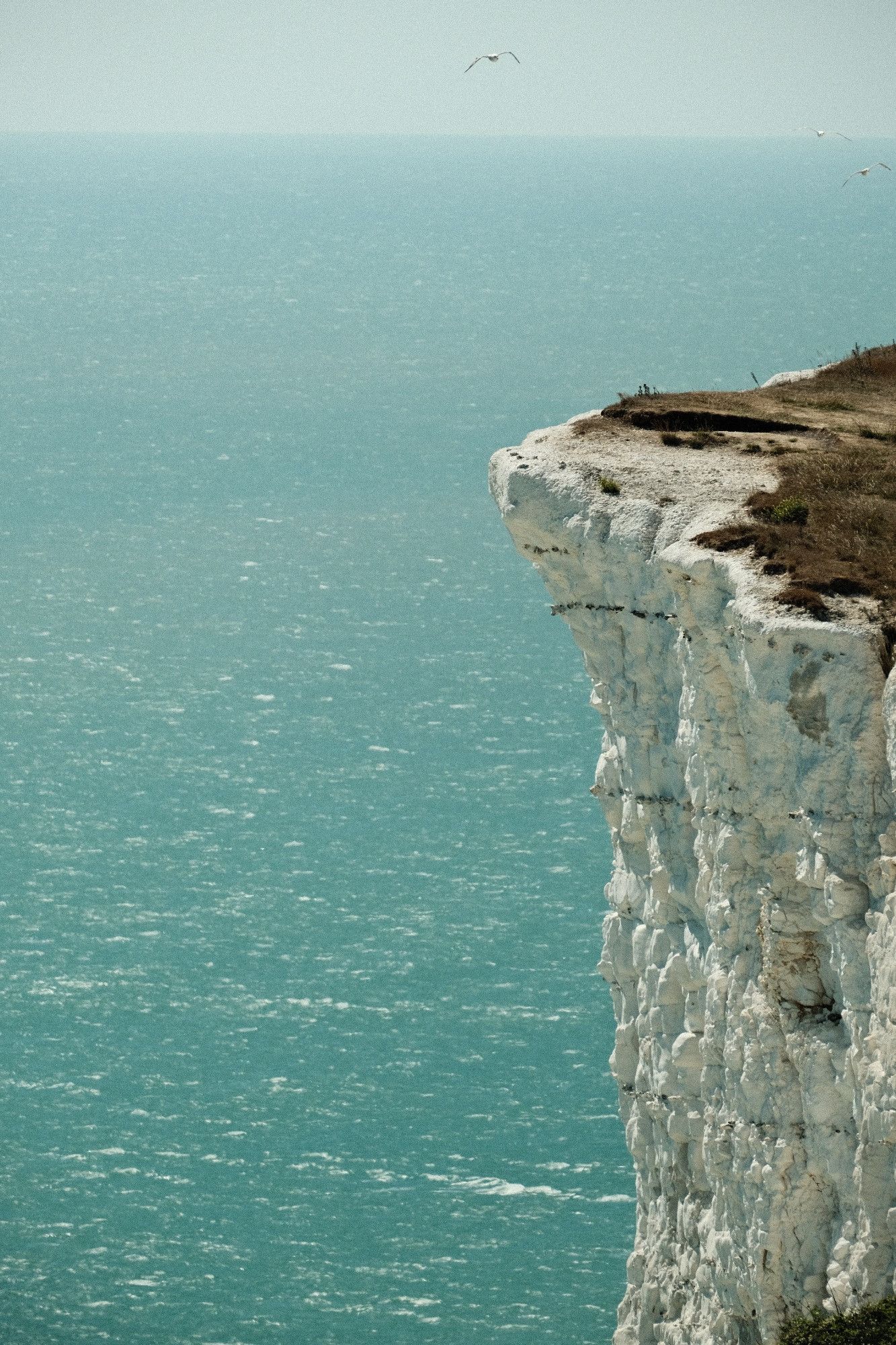 Side view at the chalk cliff with blue sea in the background.