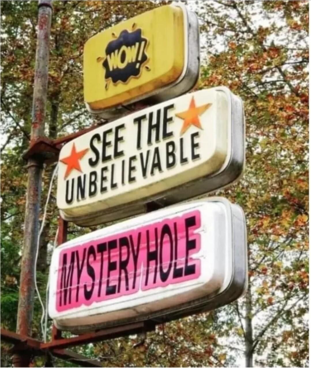 An old pole sign with three sections that say:

Wow!

See the unbelievable

Mystery hole