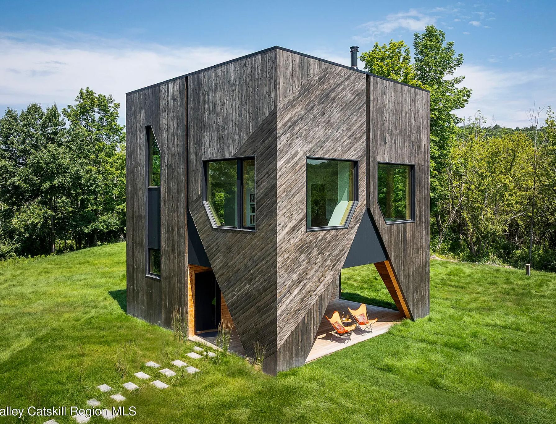 A rectangle structure made of weathered timber. It has a triangle opening at the bottom and large square windows above it. The overall effect is that it looks like something from Minecraft. 
