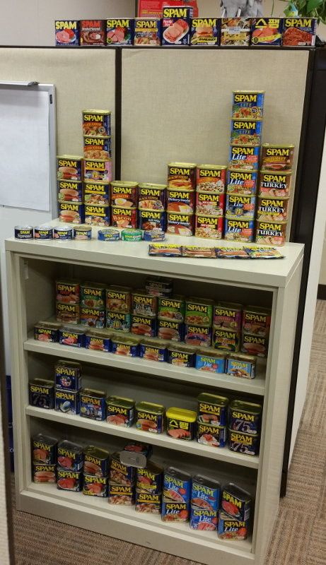 Royce's collection of SPAM cans as of 2015. Along with standard-sized cans in a variety of US domestic and international flavors, small round cans, half-height cans, and packets are also featured.