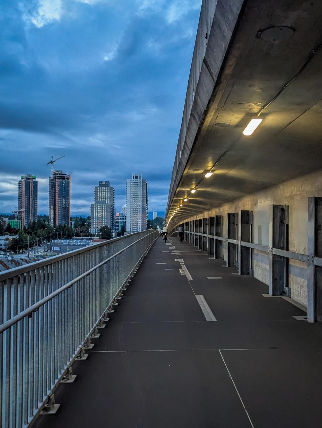 a multi-use deck of a SkyTrain bridge, with a few apartment buildings in the background