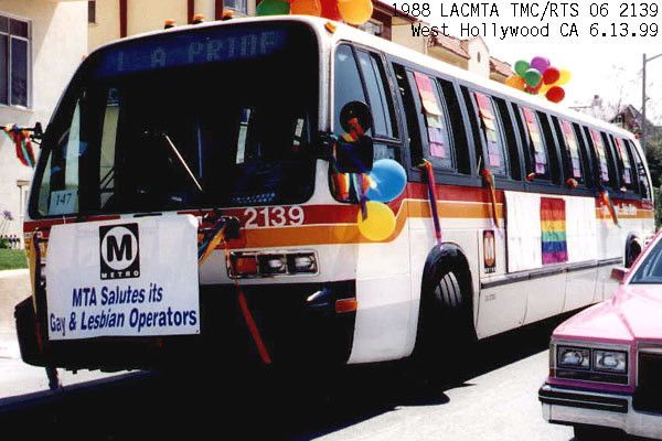 an RTS bus number 2139 covered in rainbow flag banners and balloons, with a sign on its front bike rack reading "MTA Salutes its Gay & Lesbian Operators." it is in west hollywood in 1999, head sign reading LA Pride