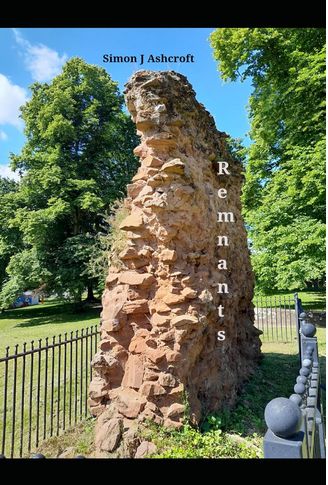 Cover of paperback edition of "Remnants".  A more or less triangular section of ruined wall, well above head height, built from sandy coloured stone.  It is within an enclosure of iron railings, about waist height, in a grassy area with trees,in full leaf, in the background.  The sky above the trees is blue, with light cloud toward the left.  The sun is shining, as a summer day.  In the blue area of sky is the name "Simon J Ashcroft" in black letters.  The word "Remnants" is in white, down the length of the ruined wall.