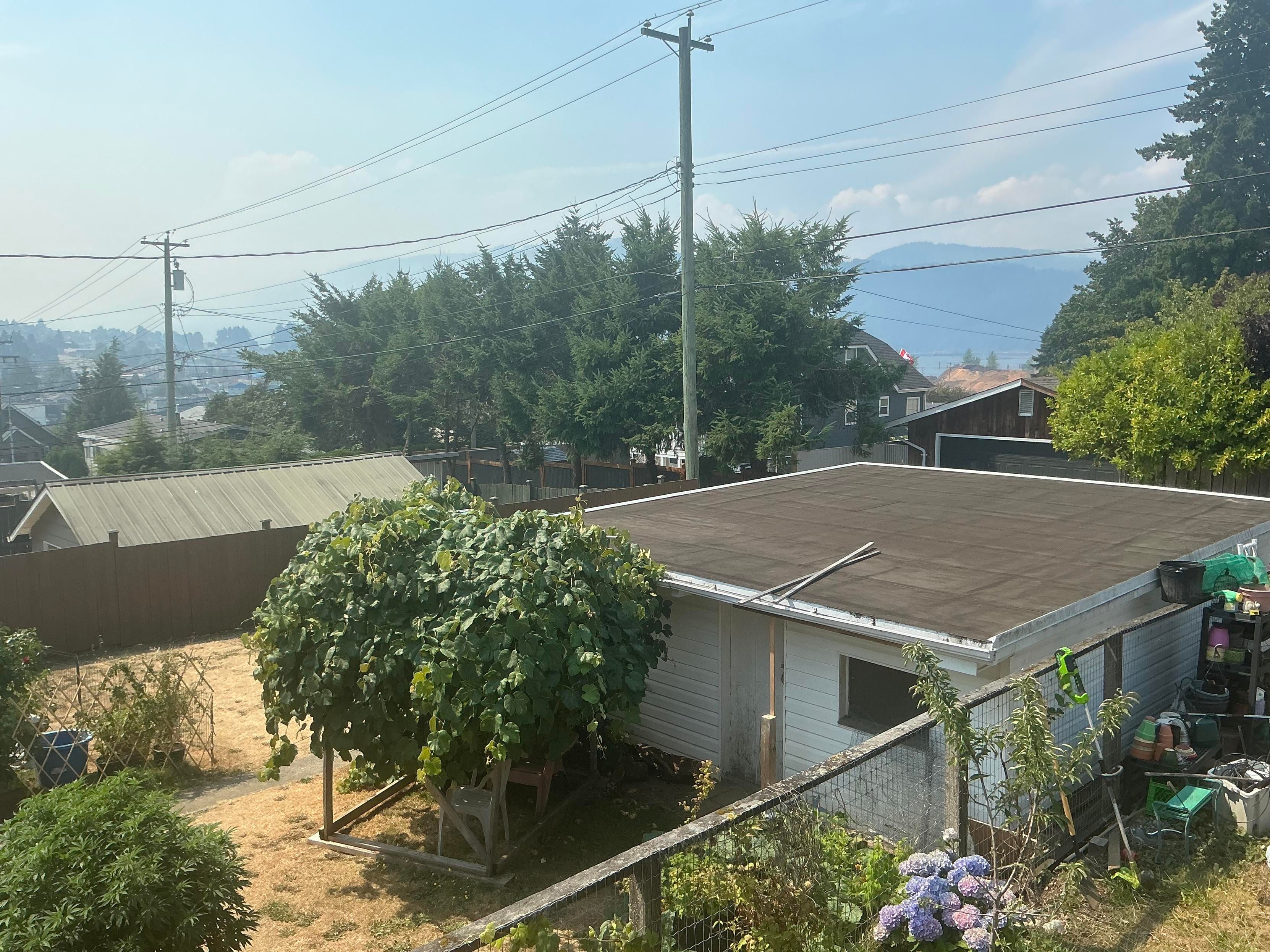 A view toward the city and inlet shows smoke hanging low obscuring the sky and hills to the south.