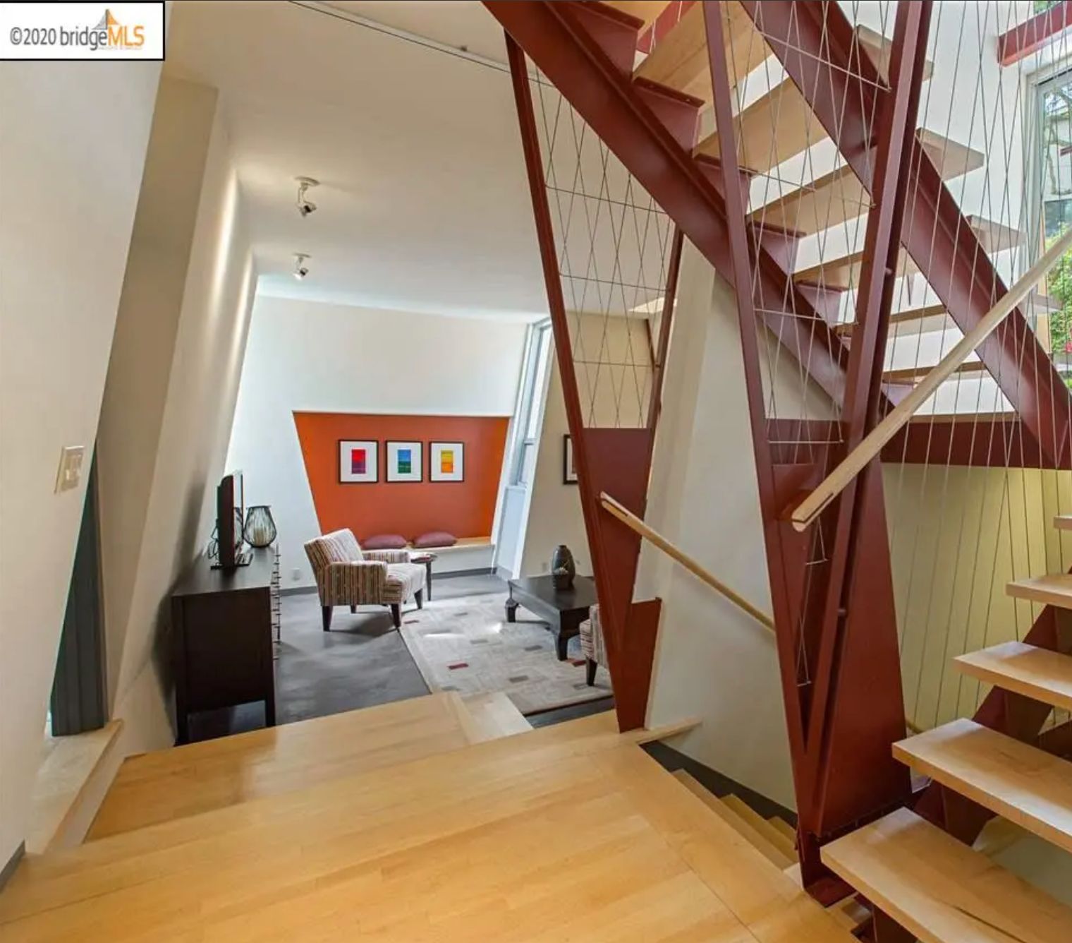 A view of the living room from the bottom floor. The walls on both sides are at a slant, including a sitting area at the far end which is orange with both sides at a slant.