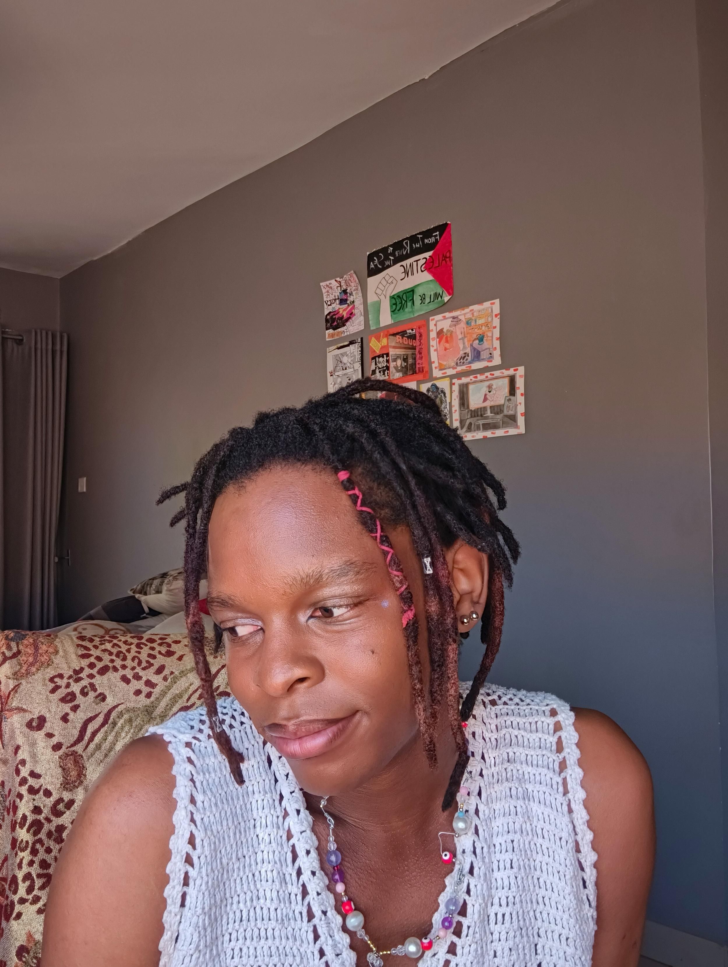 A cute black person with their makeup done posing for a portrait. All cute and blushing. With a dark lipliner.