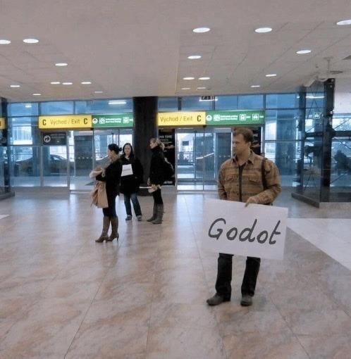 a man waiting at an airport with a sign that says Godot
