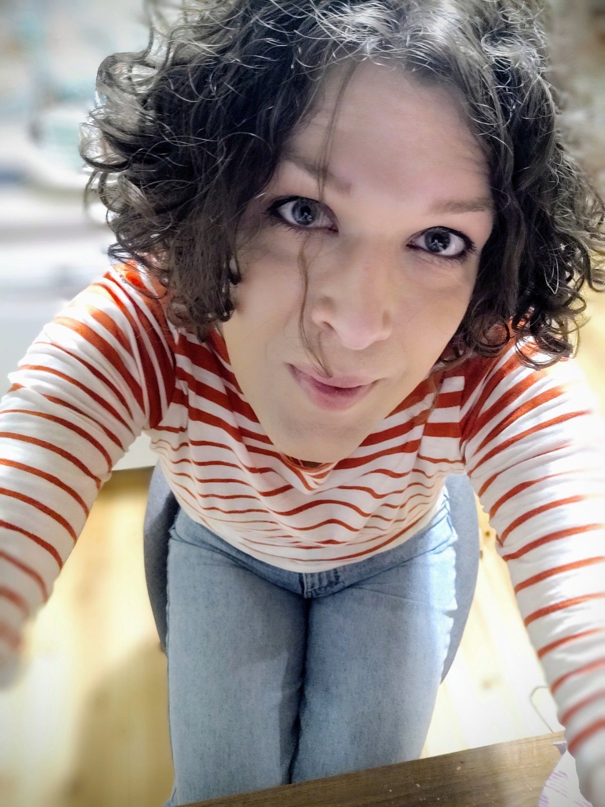 millennial selfie (taken from above with me looking up at the camera). sitting in a chair, legs held together, wearing light blue jeans and a red and white striped top