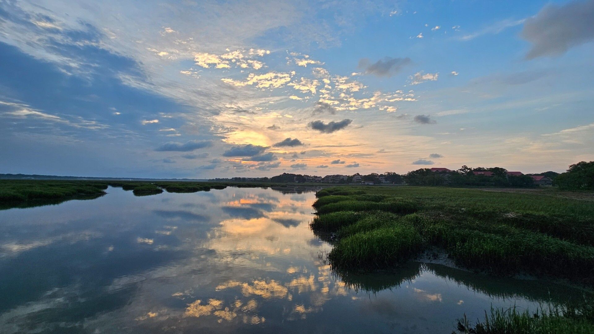 Sunrise photo across a broad creek and marsh with complex cloud structure.