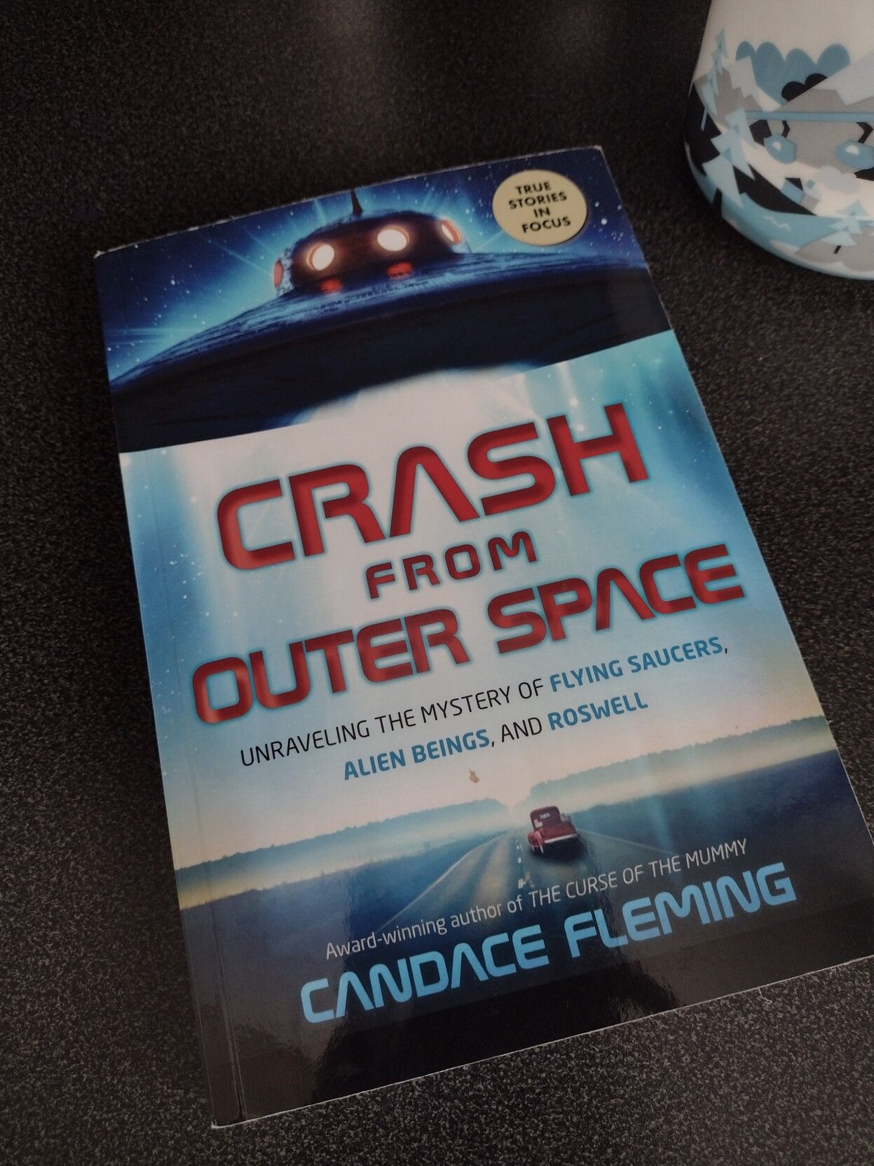 Photo of the book Crash from Outer Space by Candace Fleming. Cover has UFO hovering at the top over a lonely road. 