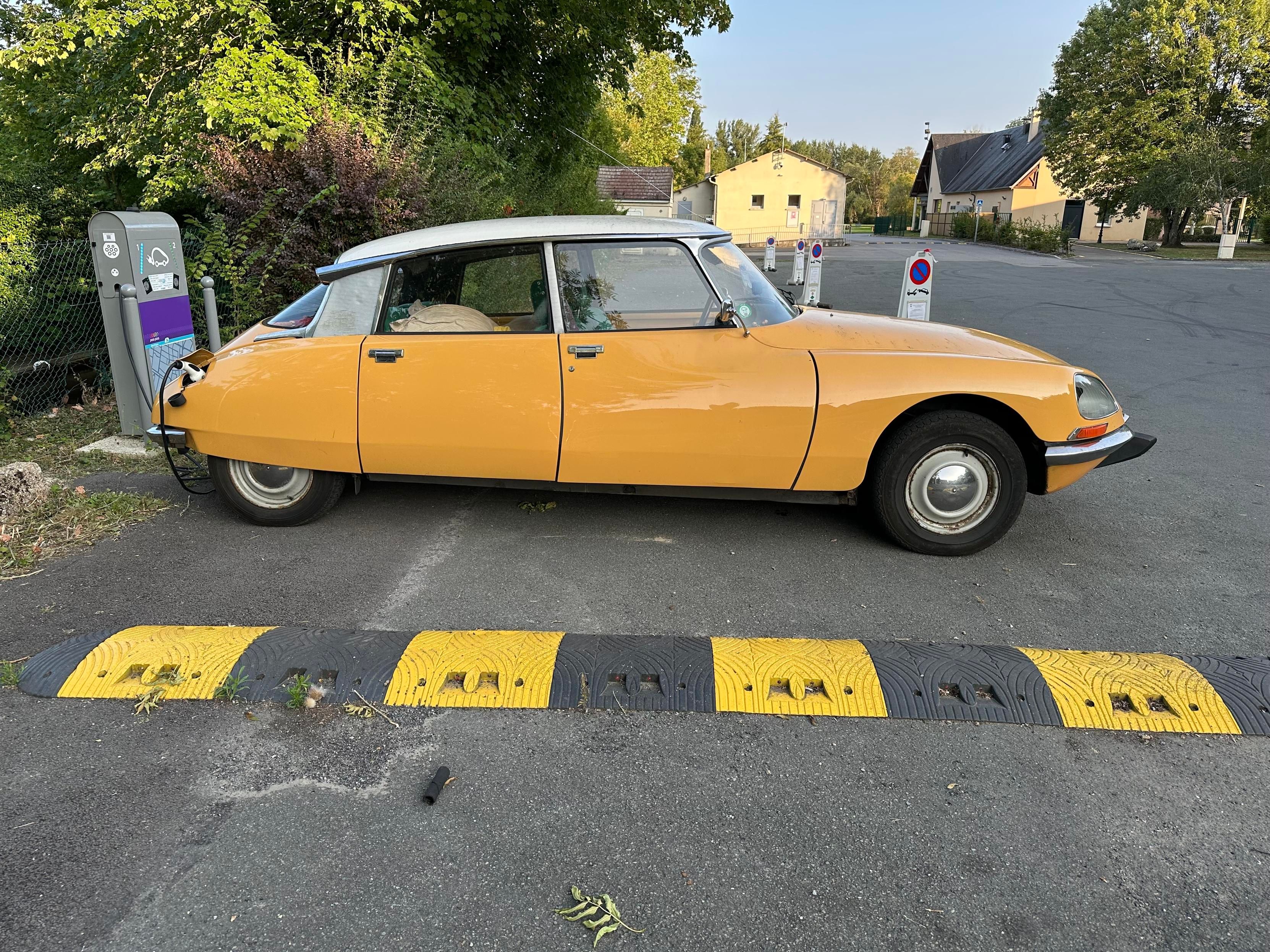 Yellow and white Citroen DS plugged into a public charger