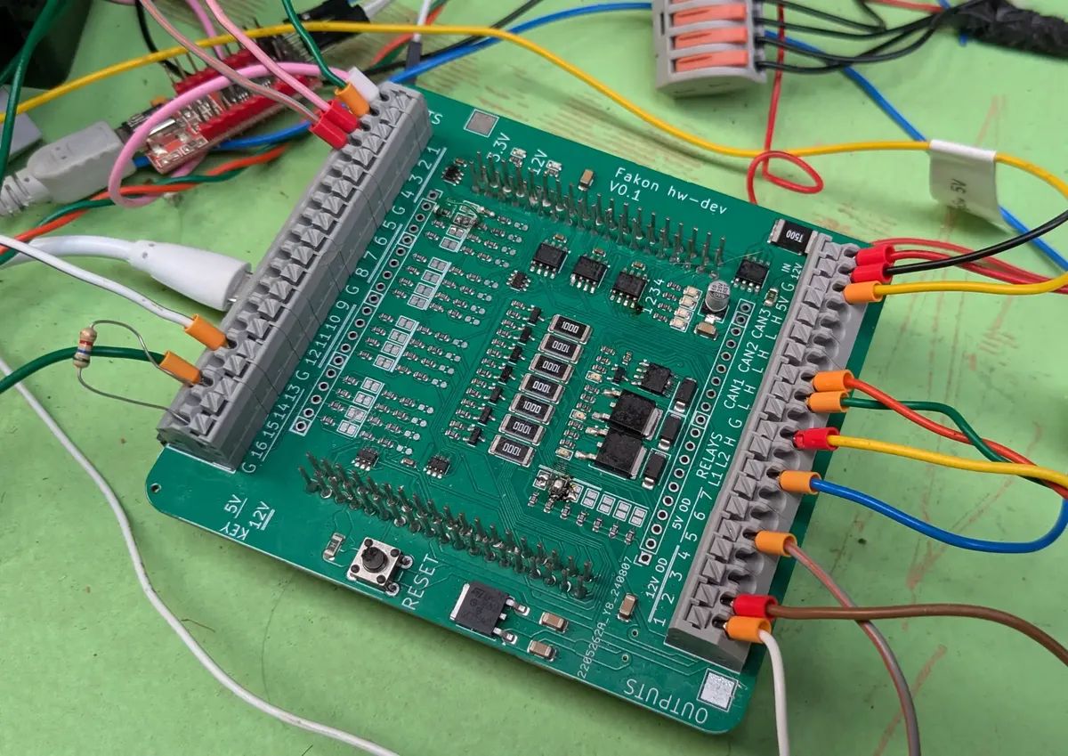 Fakon hw-dev PCB on a bench with many wires connected to it.