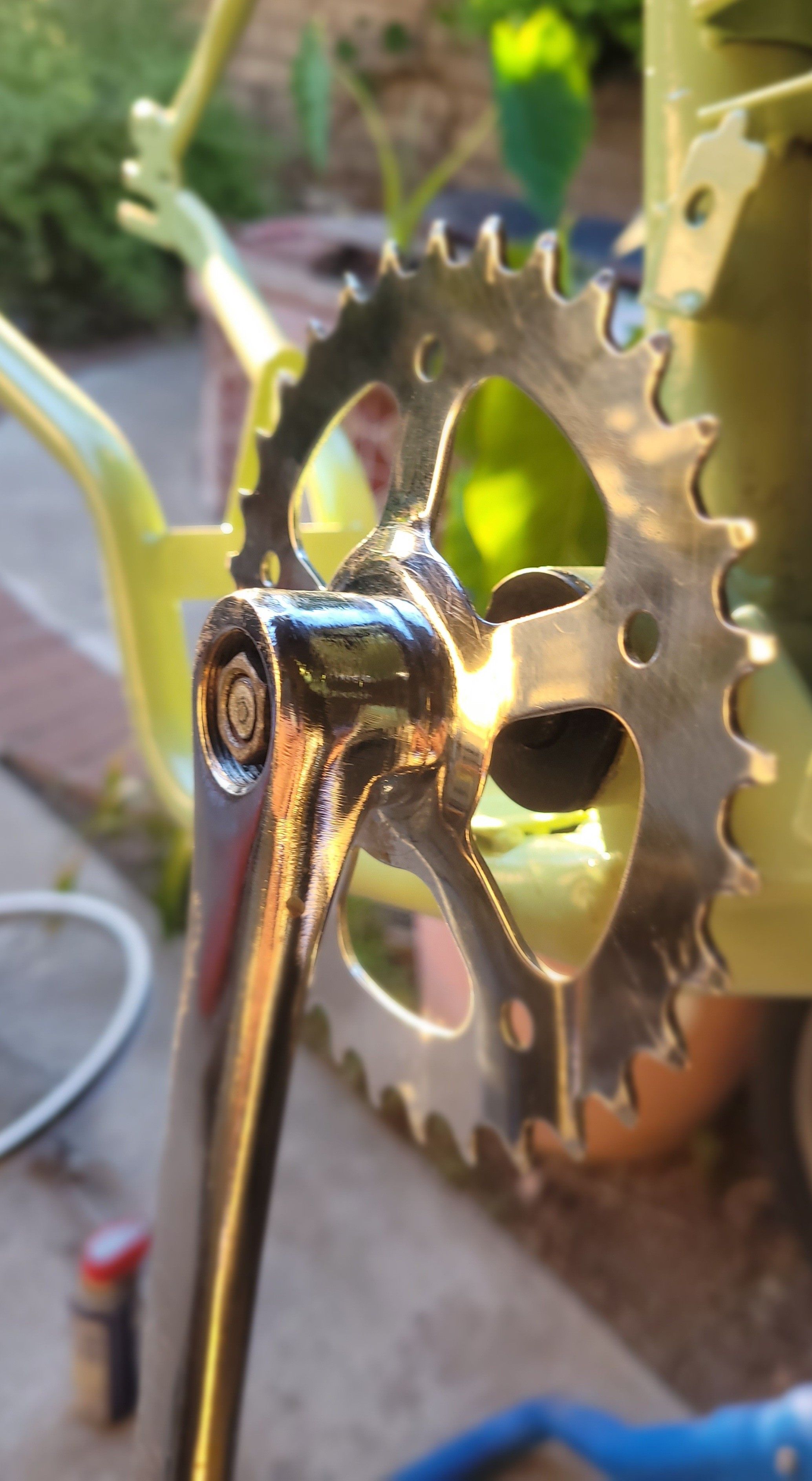 Shiny metal crank lit by late afternoon sunlight, on a stand