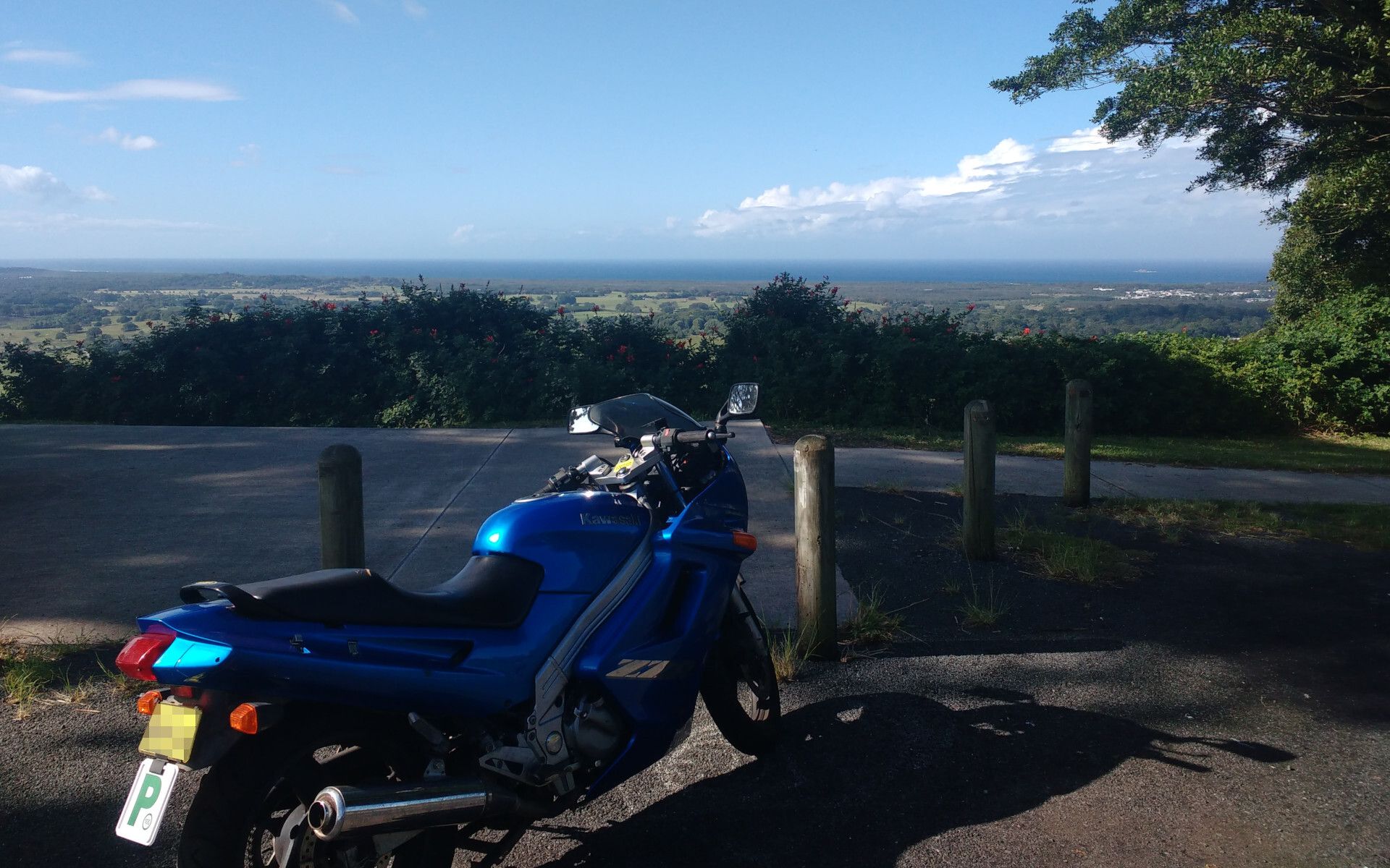 A blue Kawasaki ZZR250, parked overlooking the coast north of Byron Bay. It has full fairings, a token windscreen, fairing mounted mirrors, and a "ZZR" decal down the side.