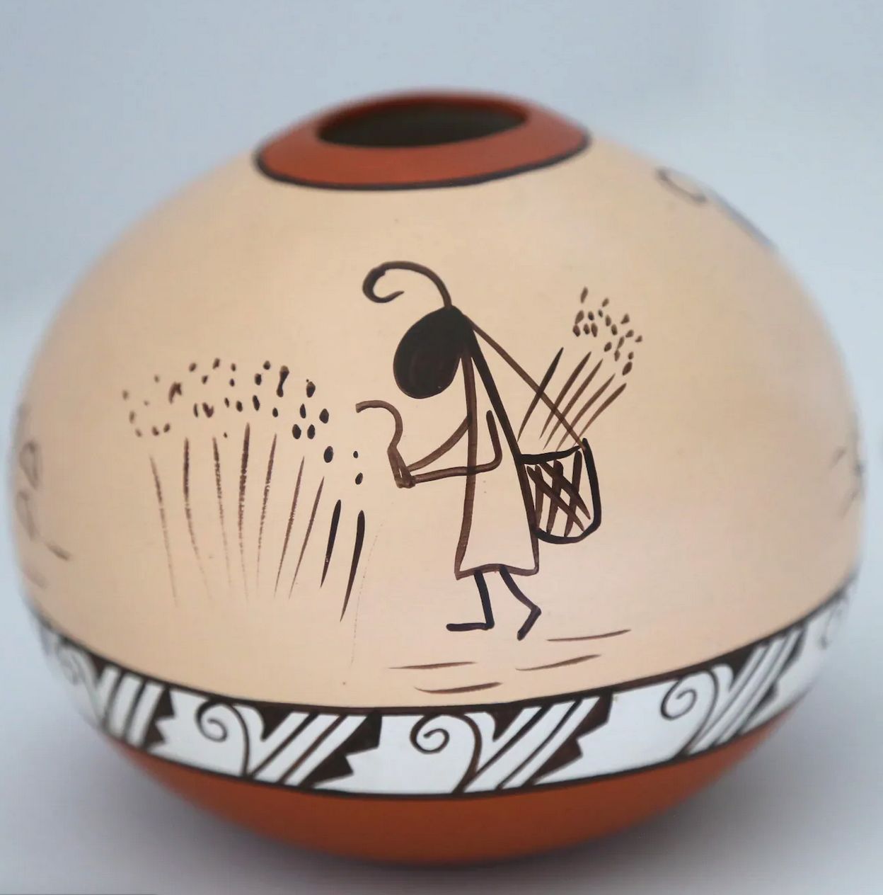 A traditional red, beige, black and white southwestern american vase. The pattern is a simple hand painted ant harvesting wheat with a basket on her back. 